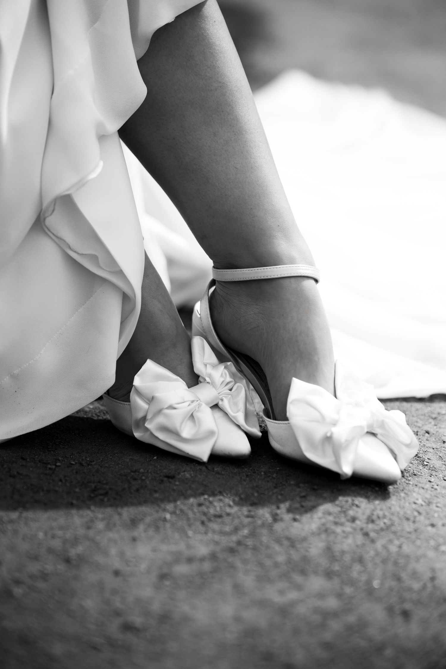 Close-up sequence of white wedding dress hem and shoes on textured ground.