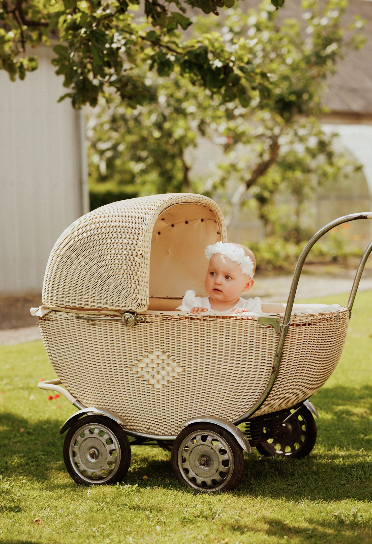 Vintage wicker baby carriage photographed in sequence on sunny green lawn.