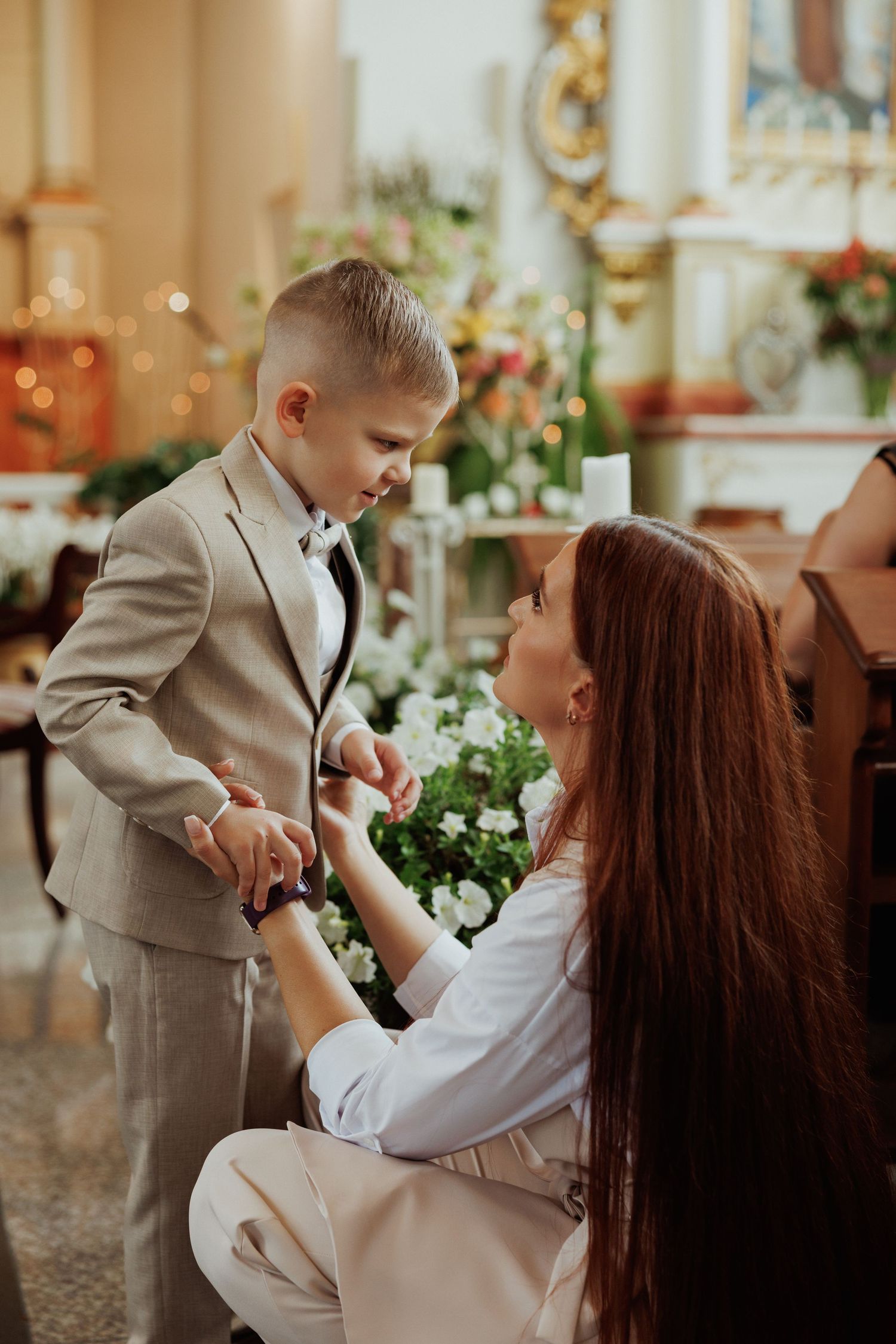 Sweet candid moment captured between parent and child in a warm, sunlit room with floral decorations.
