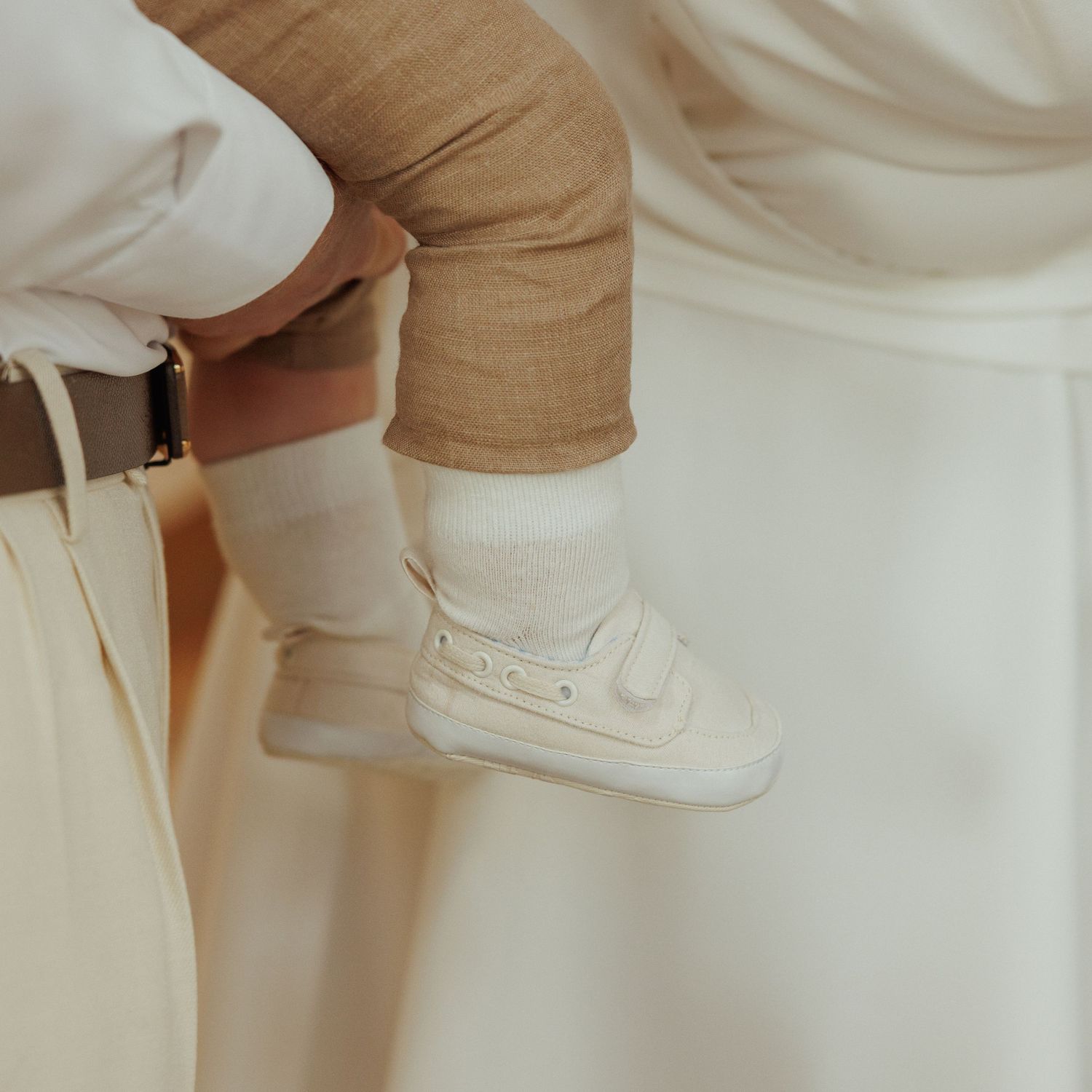Close-up view of someone wearing white sneakers and tan pants showing different angles and positions of the footwear.