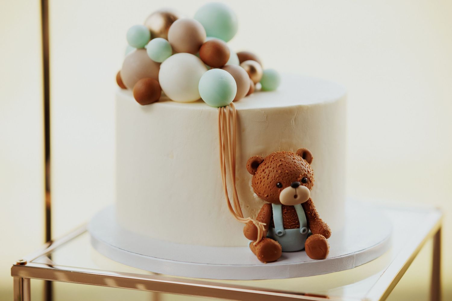 Pastel-colored cake decorations and teddy bear toppers adorn a white tiered celebration cake.