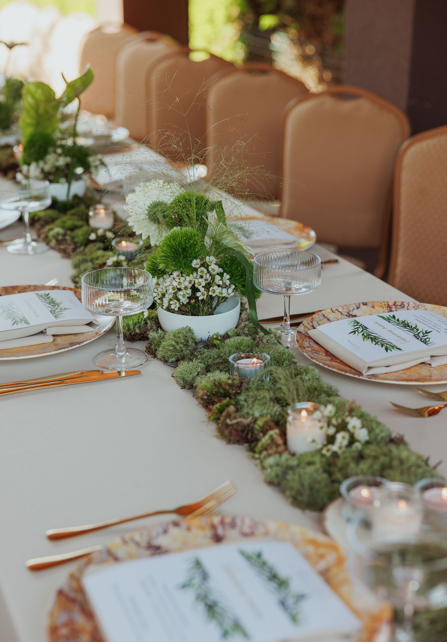 Elegant table setting with greenery runner and white place settings for special event.