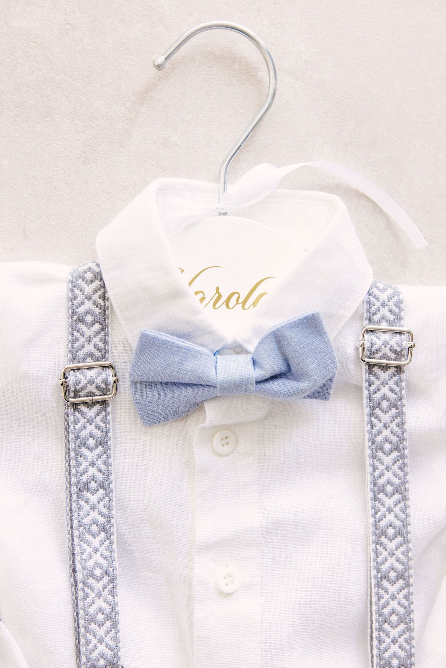 White baby dress hangers with decorative gray and white patterned straps and light blue bow accents.