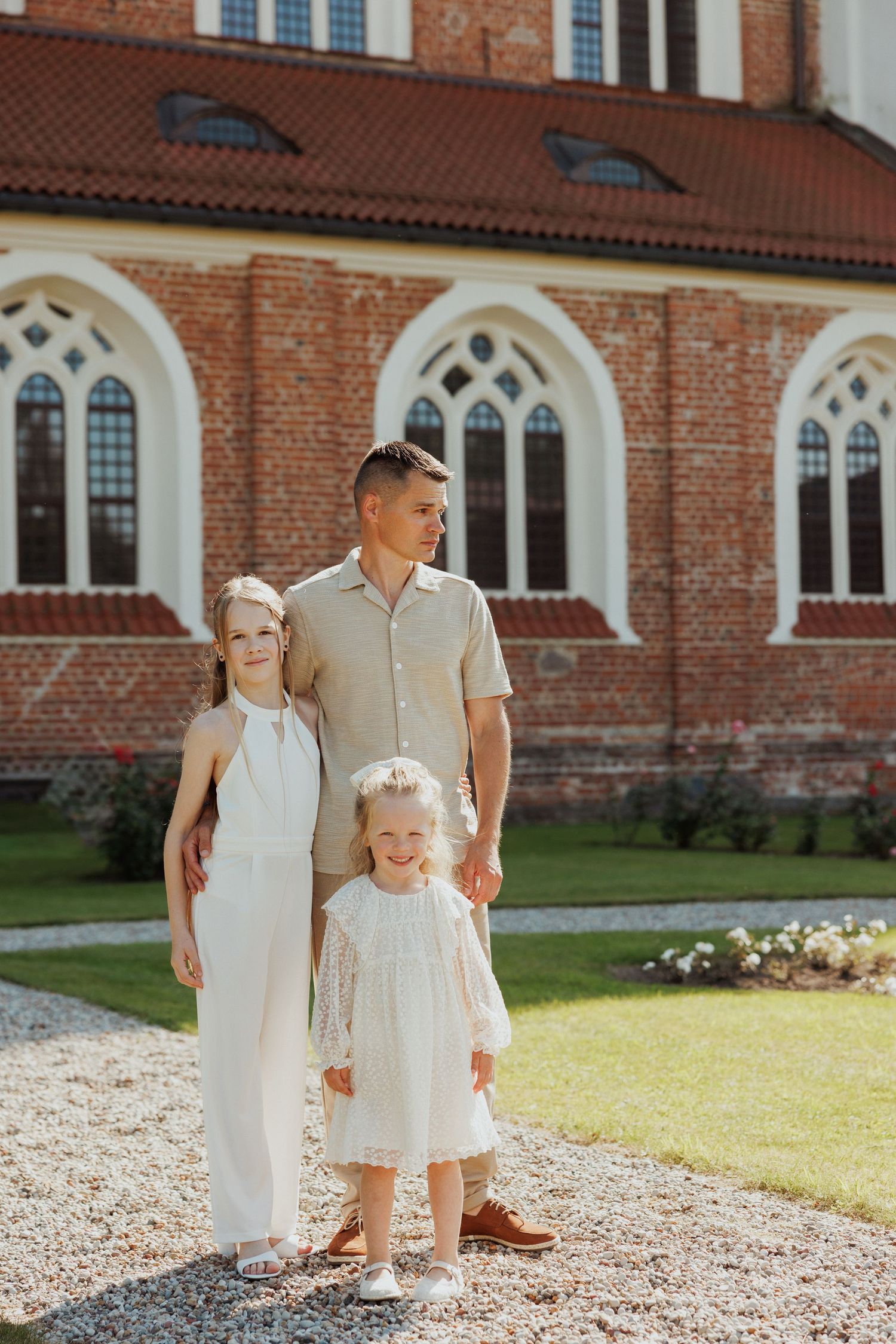 Small group posing together on gravel path next to traditional brick church architecture.