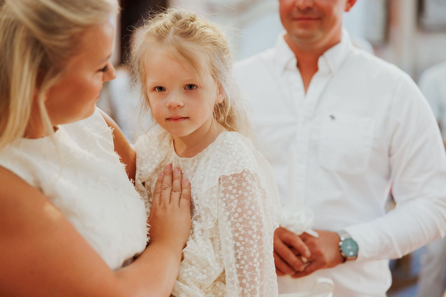 A series of candid wedding moments showing people in white attire embracing and interacting during a celebration.