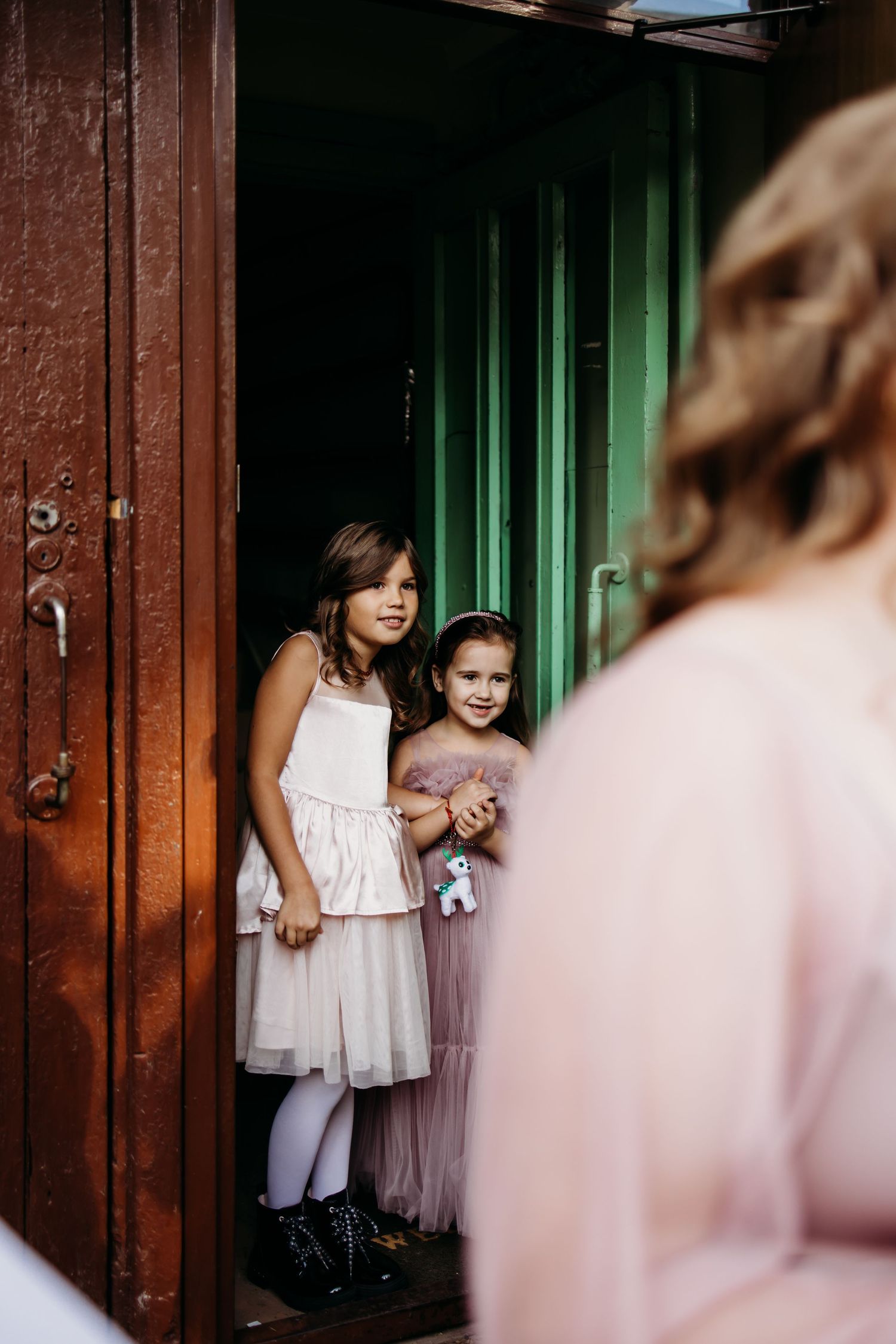 Series of artistic wedding photos showing a young girl in a white dress standing against a dark wooden door with green light.