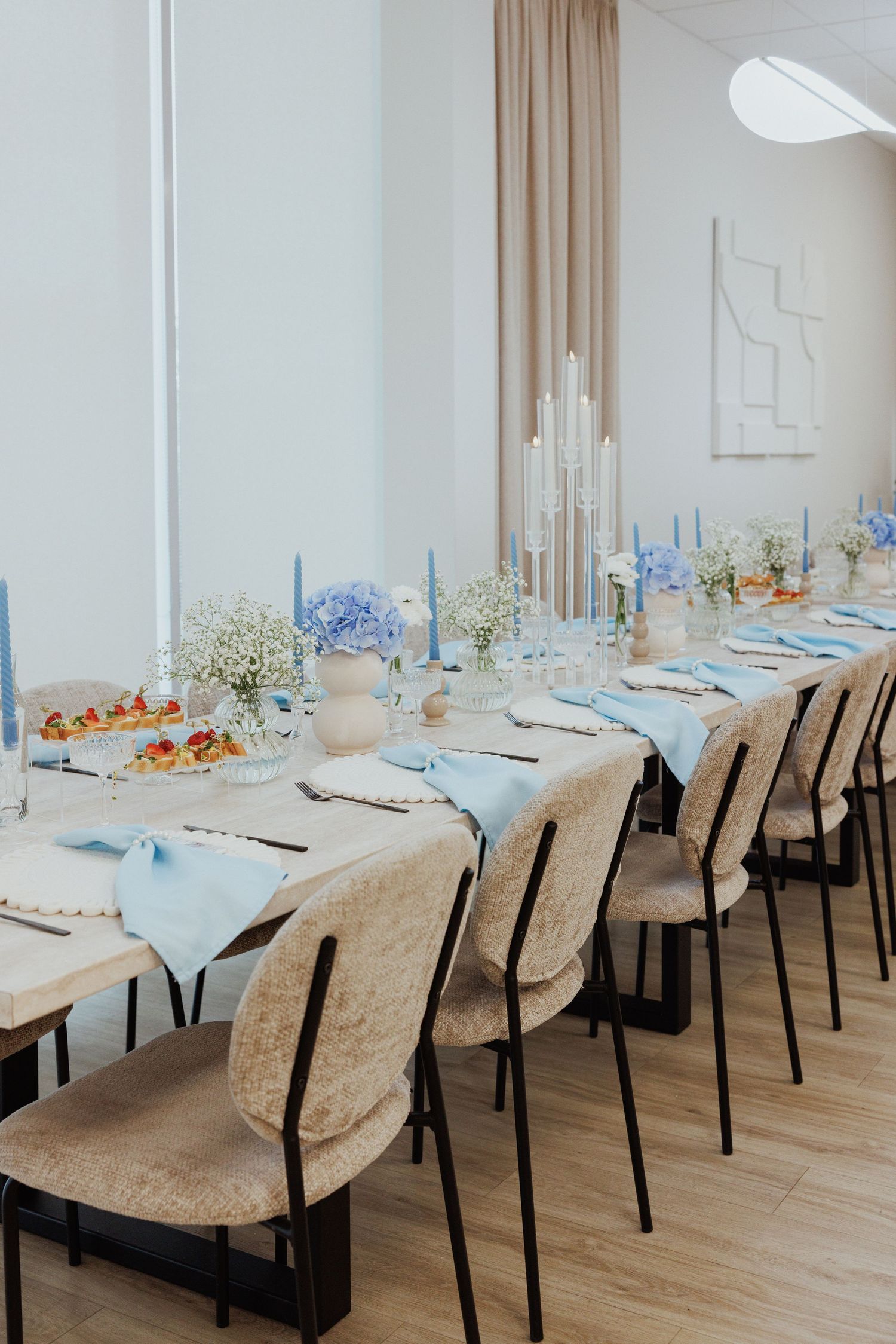 Formal dining setup with upholstered chairs and blue table settings in a bright room.