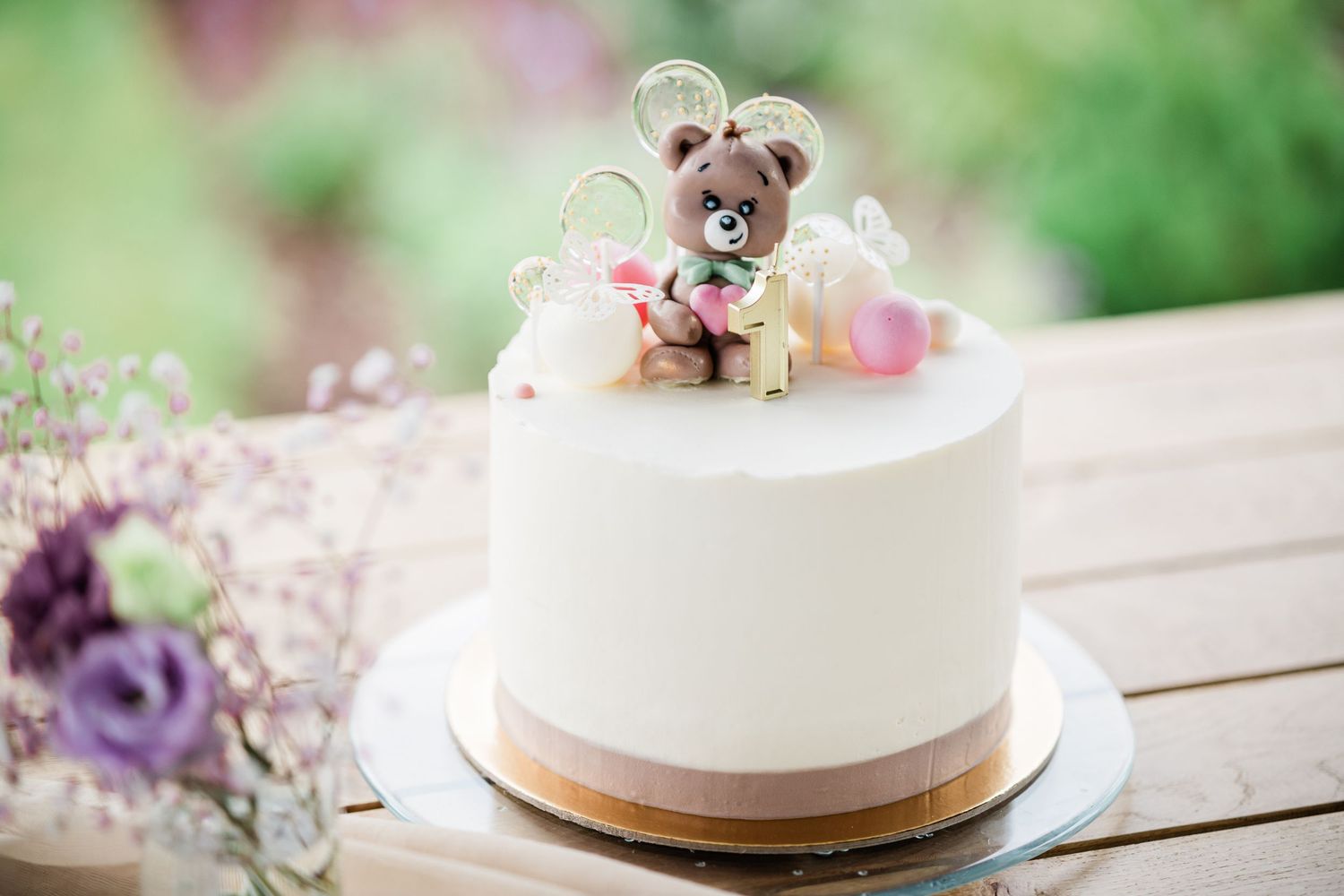 Elegant white wedding cake decorated with flowers and placed on an outdoor table.