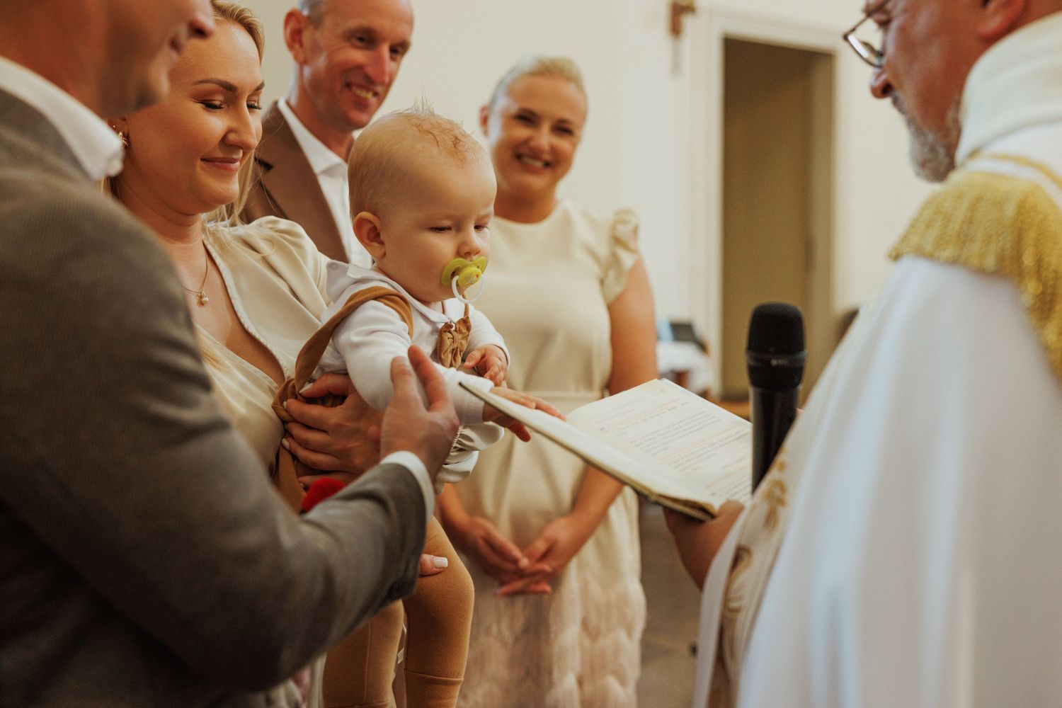 A candid moment captured during a wedding celebration showing guests interacting in a warmly lit indoor setting.