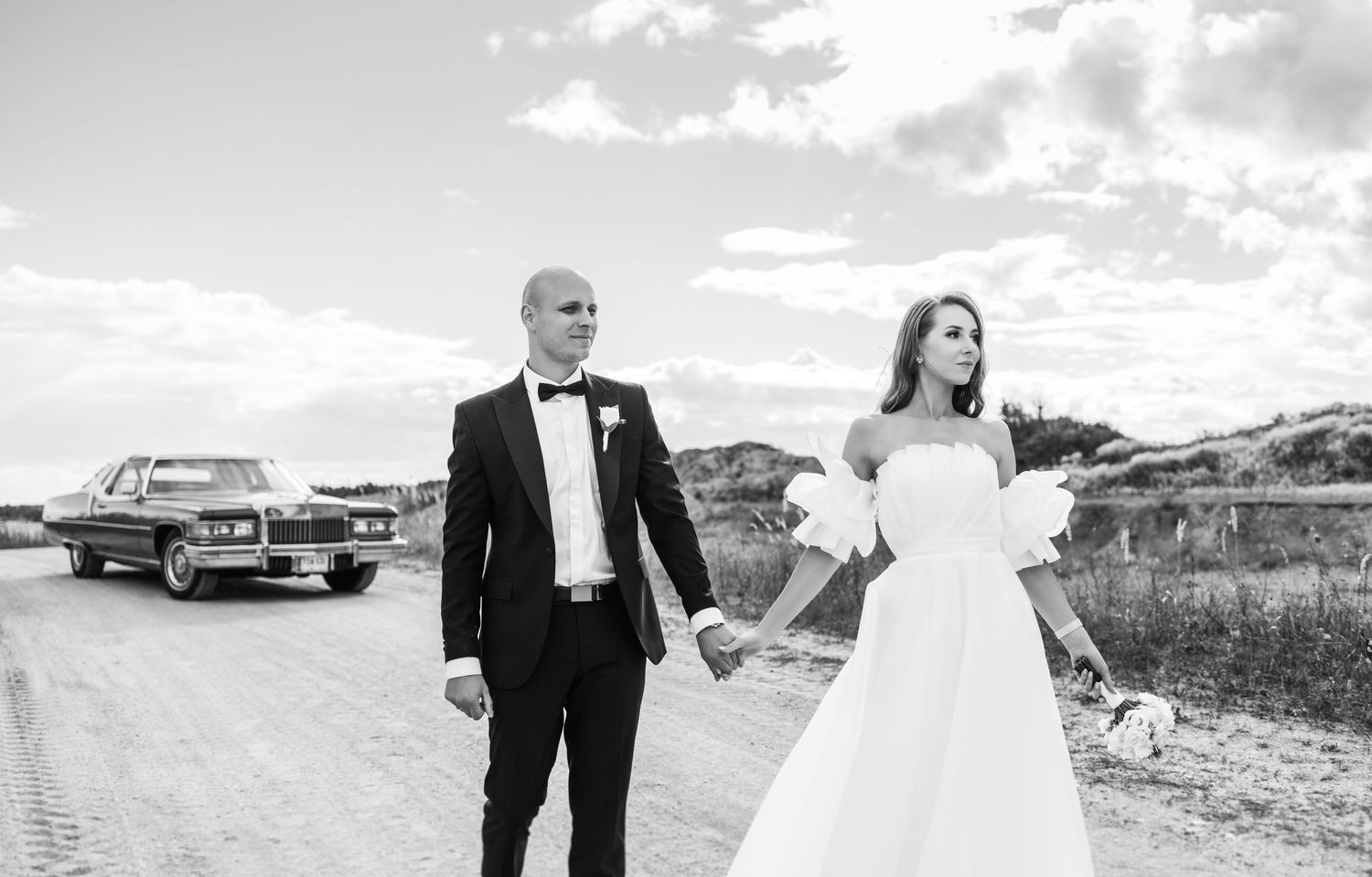 Black and white wedding portraits featuring couple and classic car in scenic outdoor setting.