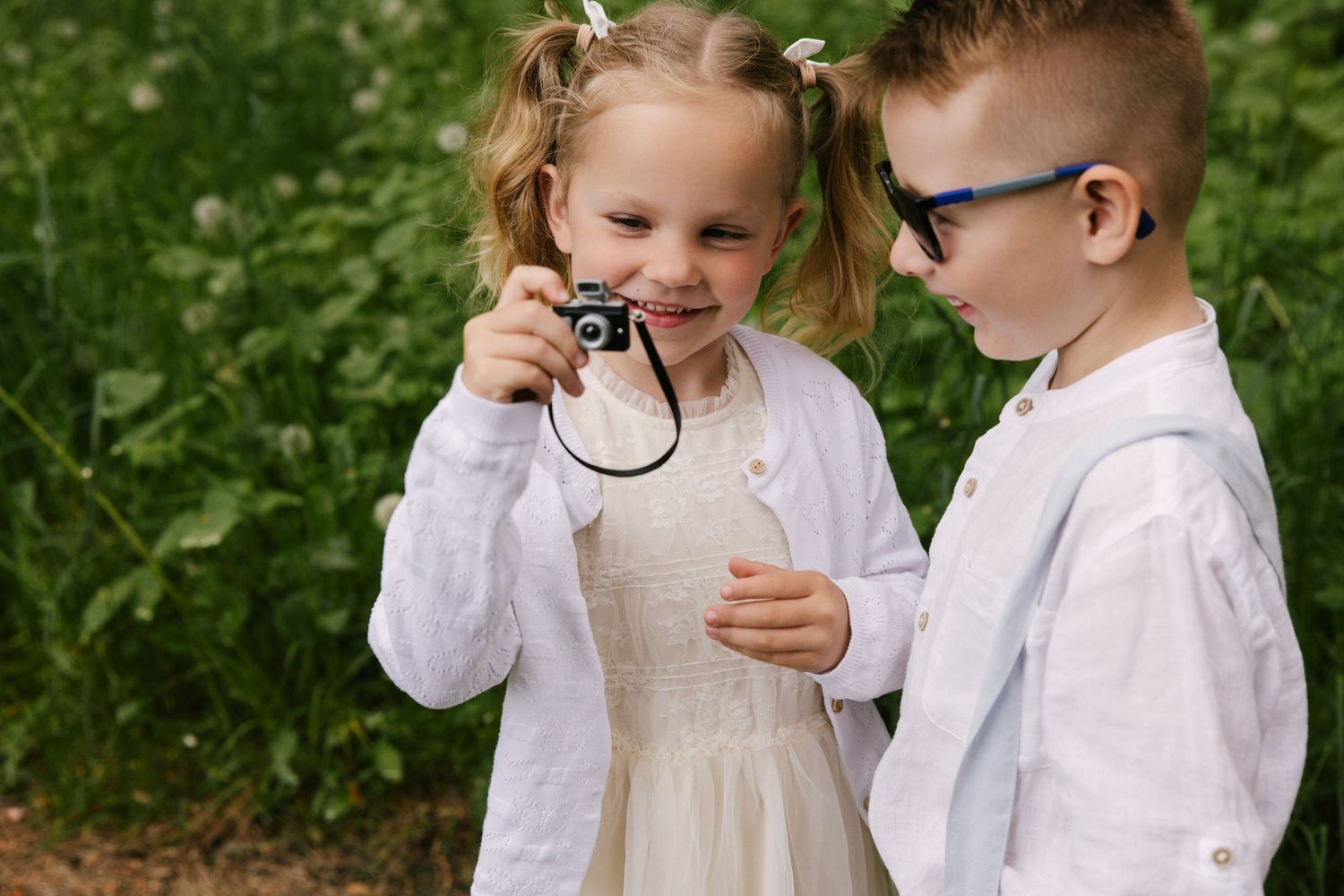Playful candid shots of children in white attire exploring a forest setting.