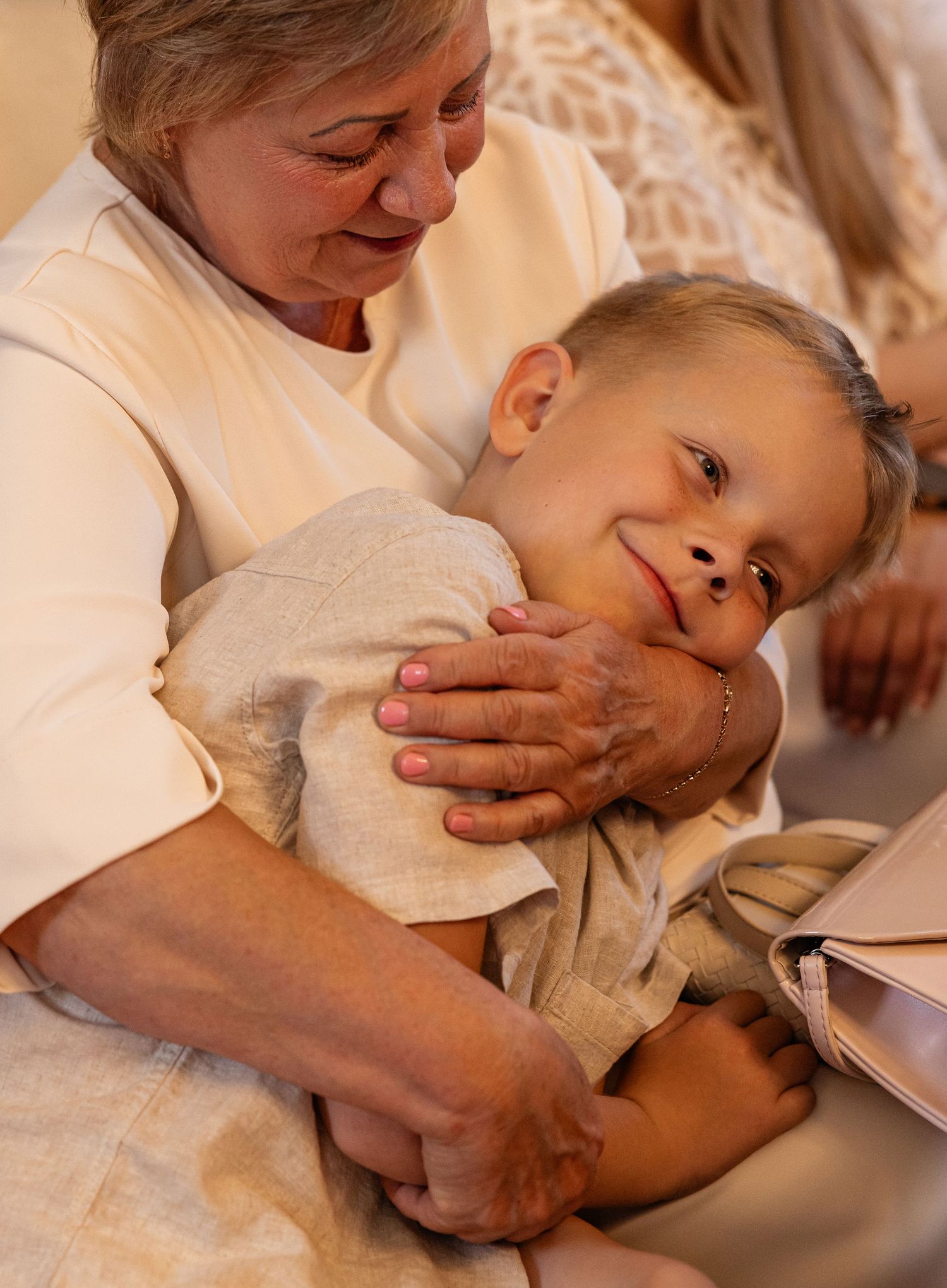 A grandmother tenderly embraces a smiling young boy in a warm and loving indoor moment.