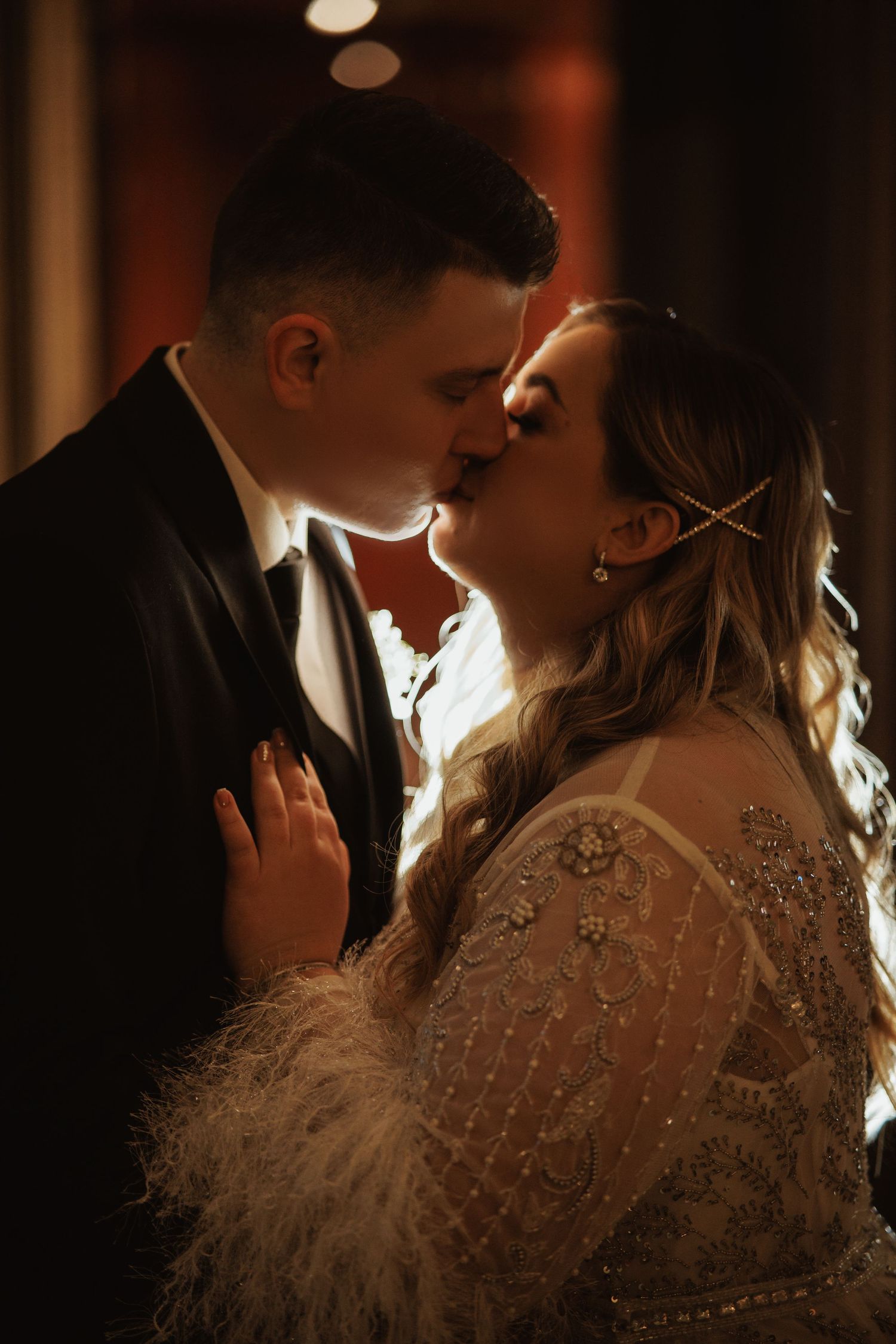 Romantic couple in formal wear share an intimate moment in moody lighting with a vintage-inspired beaded dress.