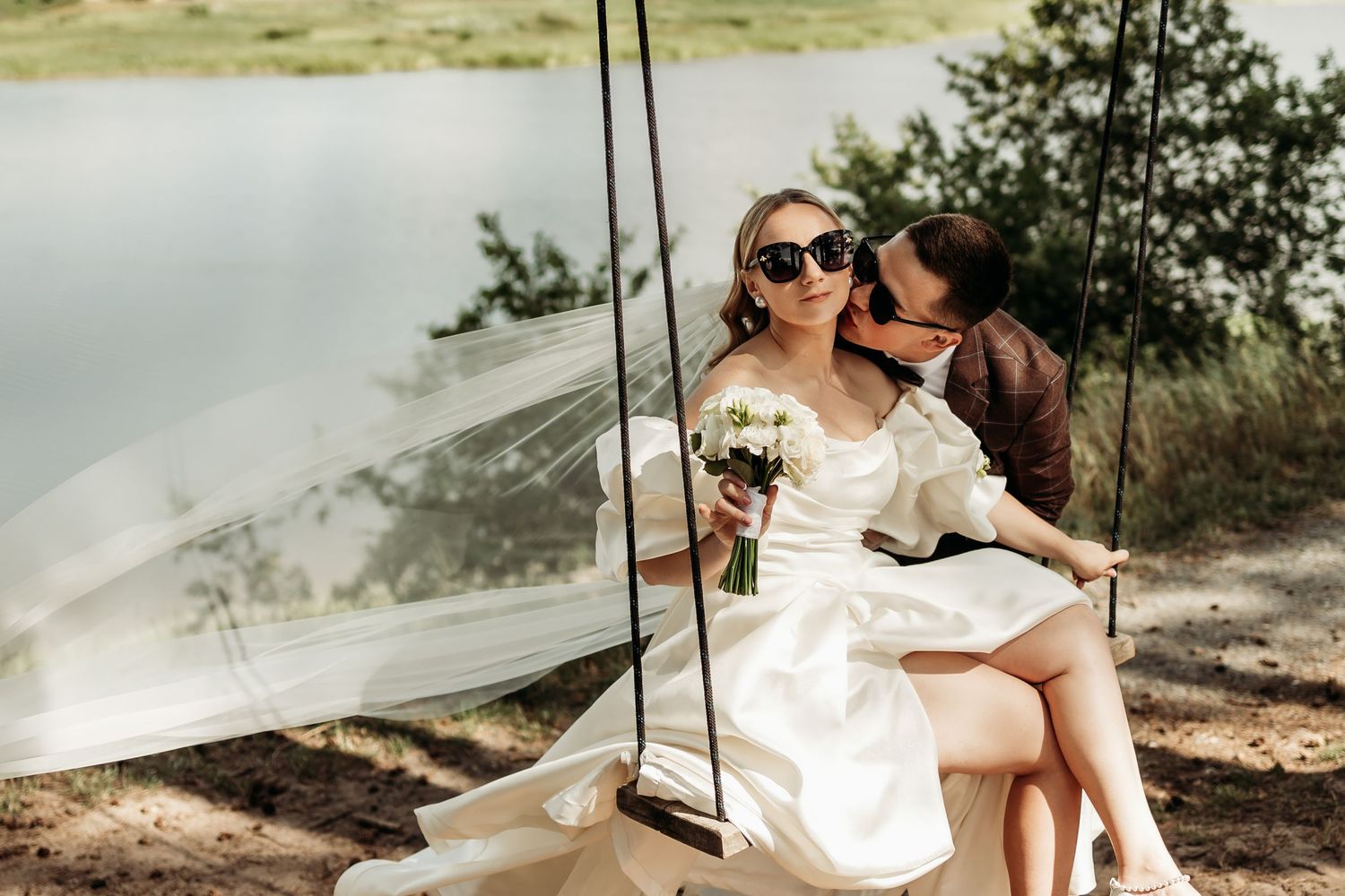A romantic wedding photo series showing a couple in a dreamy outdoor setting with flowing white fabric.