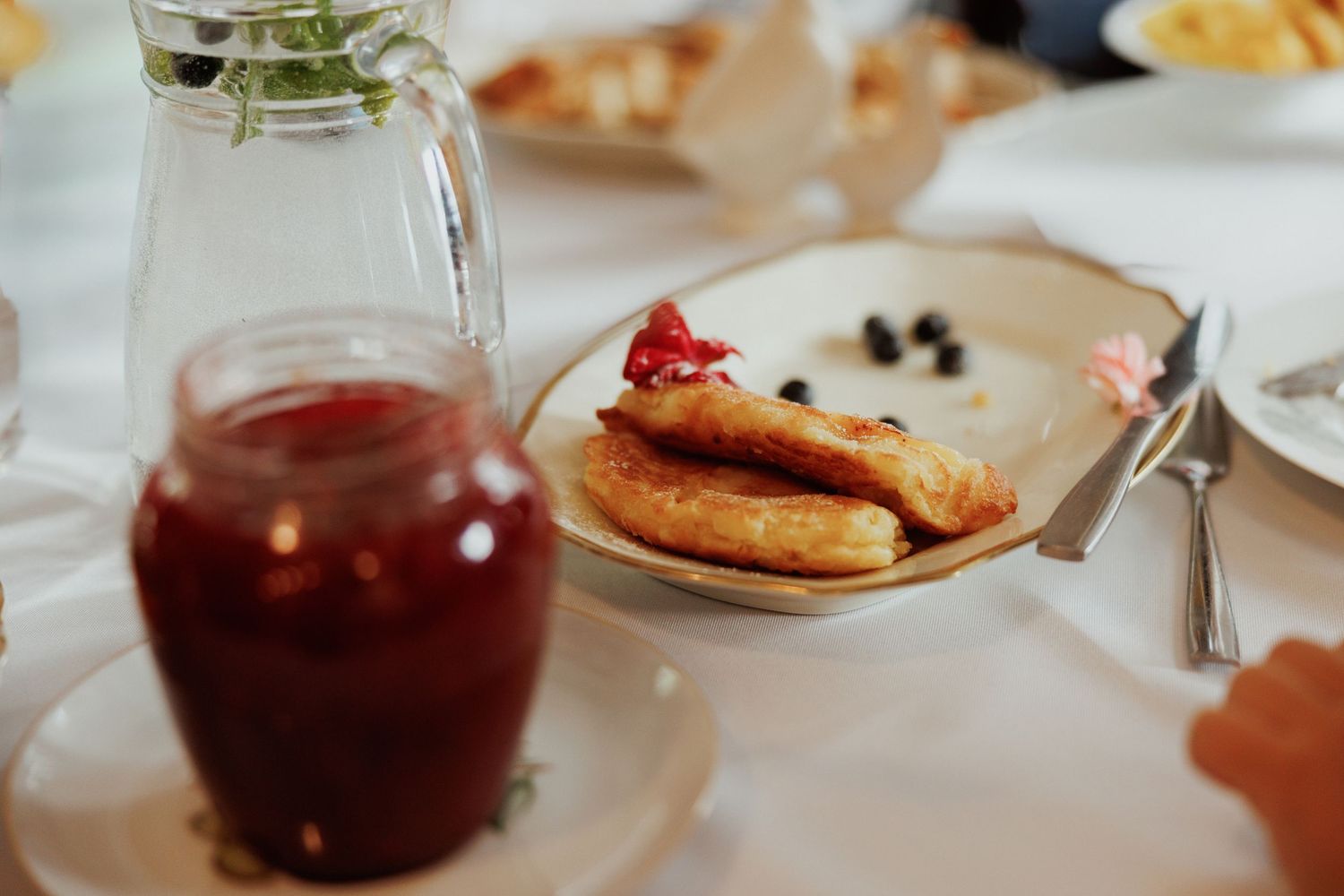 Red beverage in glass cups served alongside pastries on an elegant table setting.