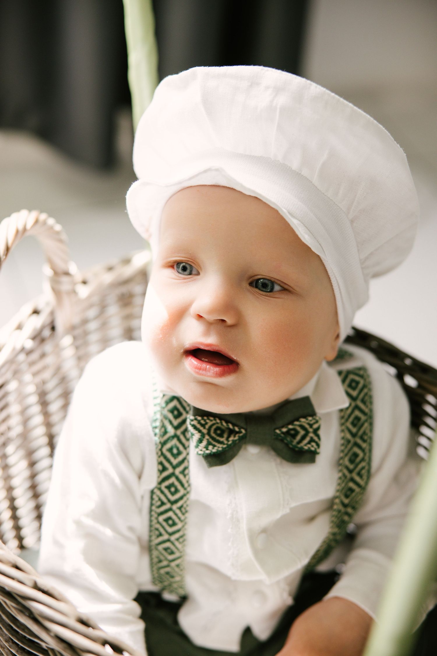 A baby wearing a white chef's hat and geometric patterned bow tie smiles in a series of close-up photos.