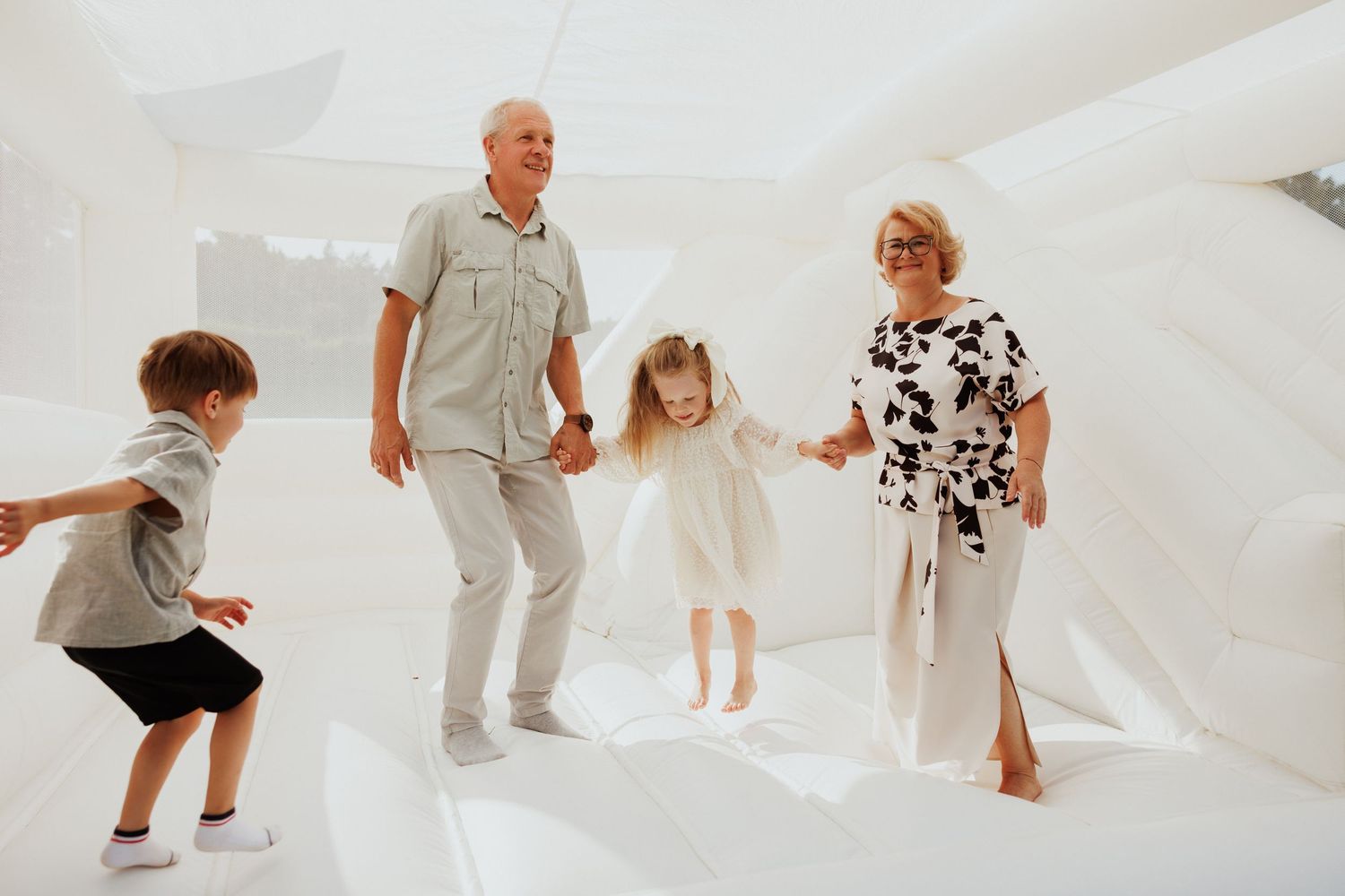 Children playing and running on white backdrop during studio photography session.