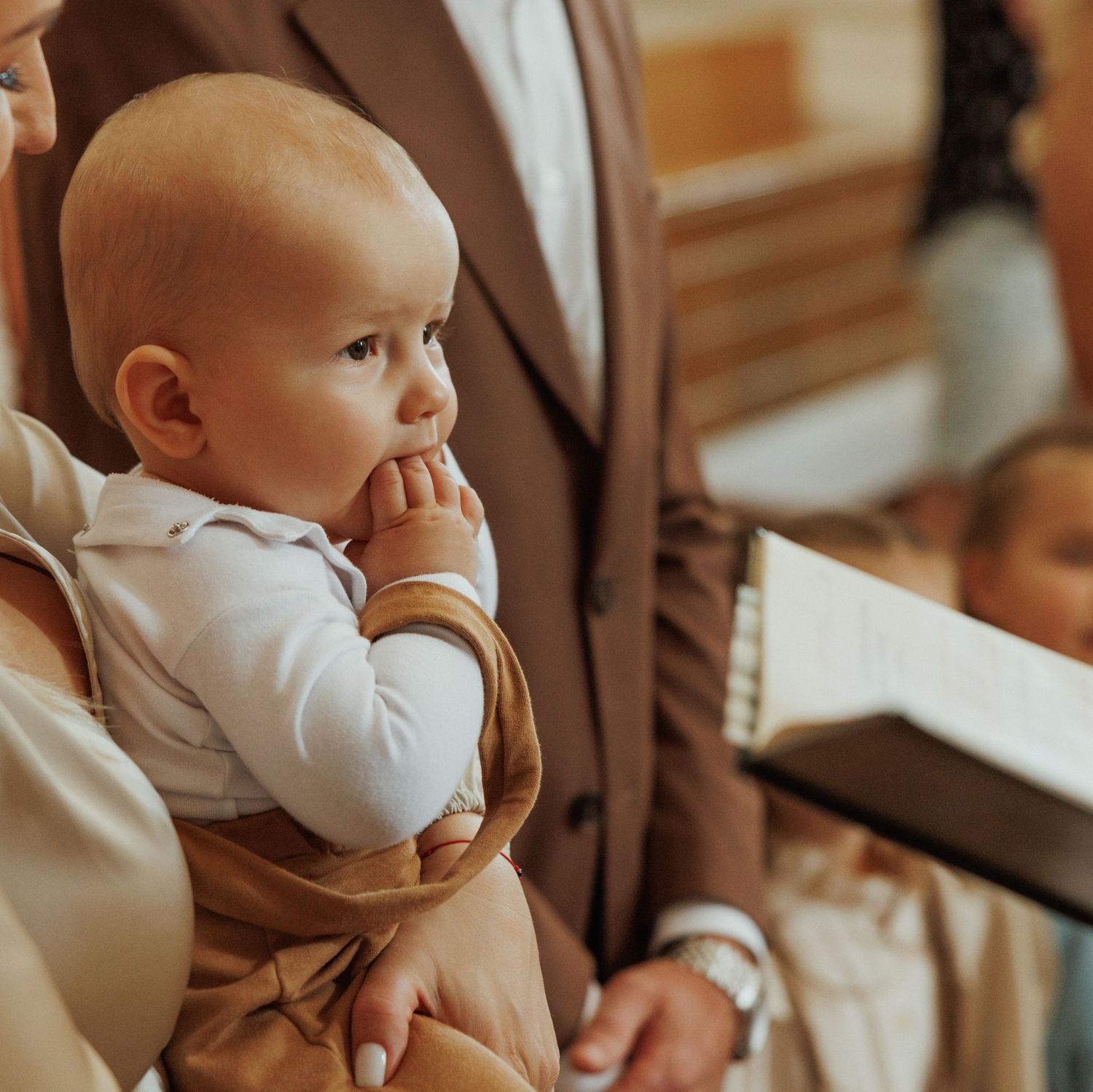 Small child in white clothing sitting during a church service.