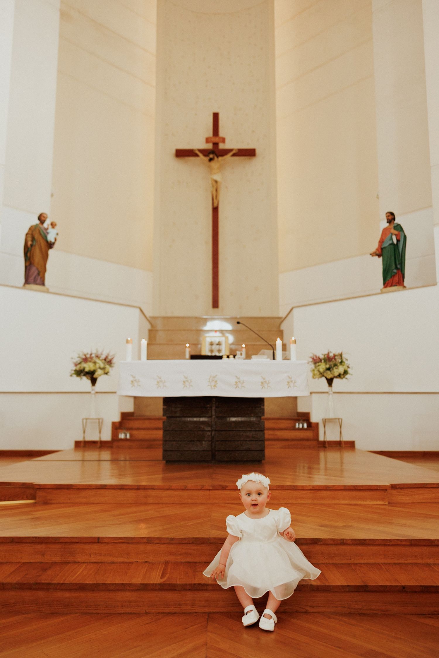 A series of photos showing a small child in white dress sitting on wooden church altar steps with crosses and candles visible.