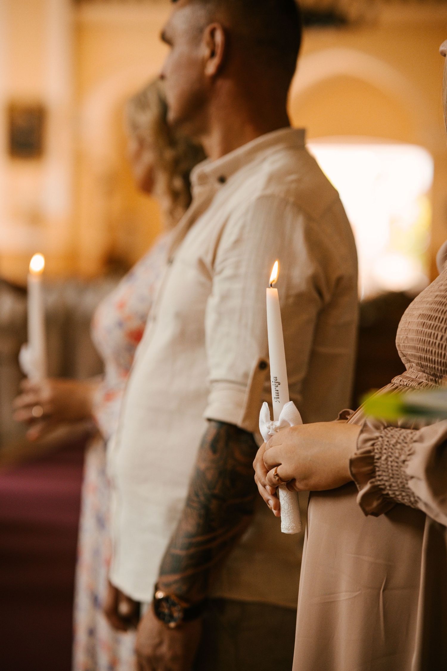 People stand in a row holding lit candles during an evening church service or ceremony.