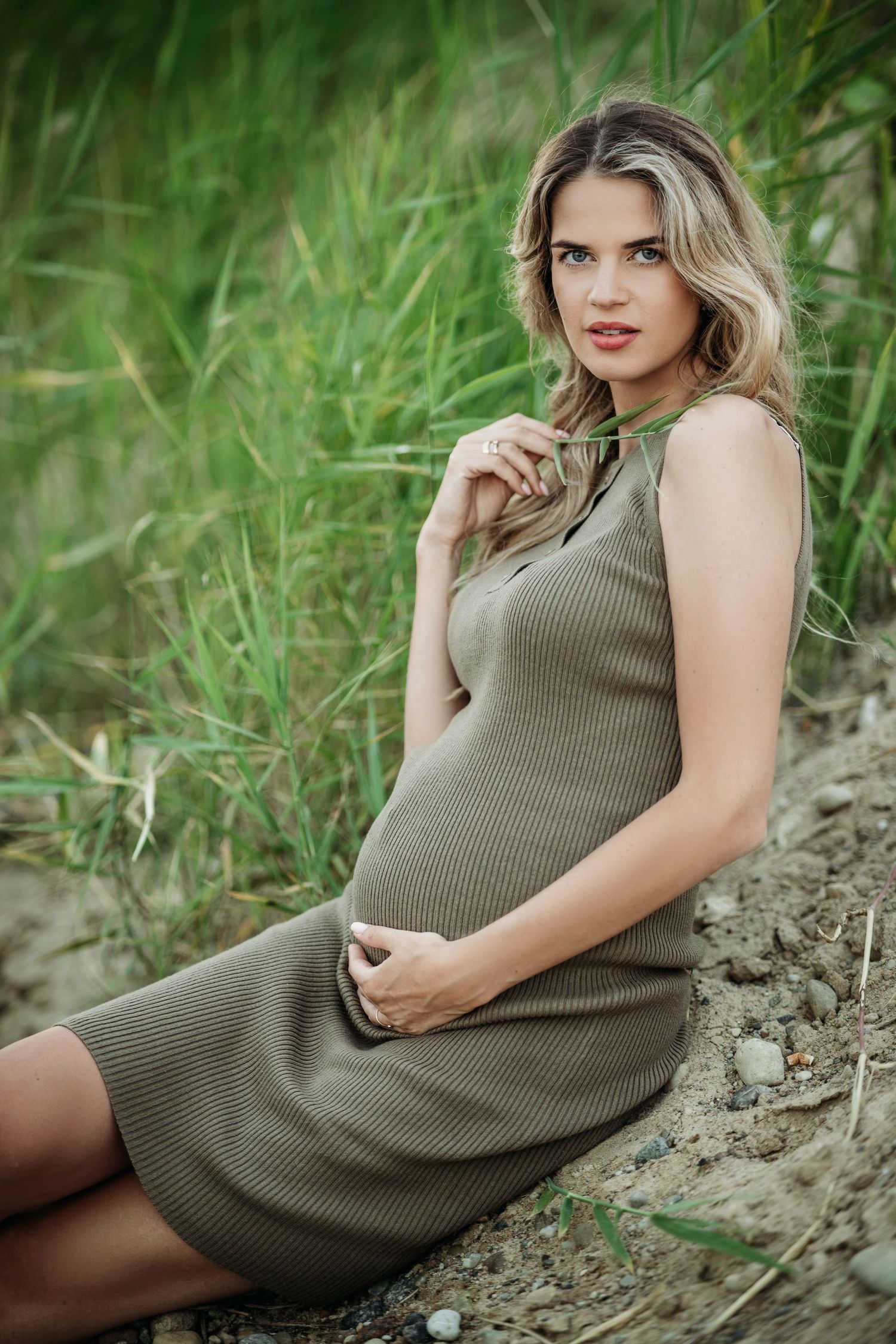 Intimate maternity session featuring an olive ribbed dress on a natural earthen slope.