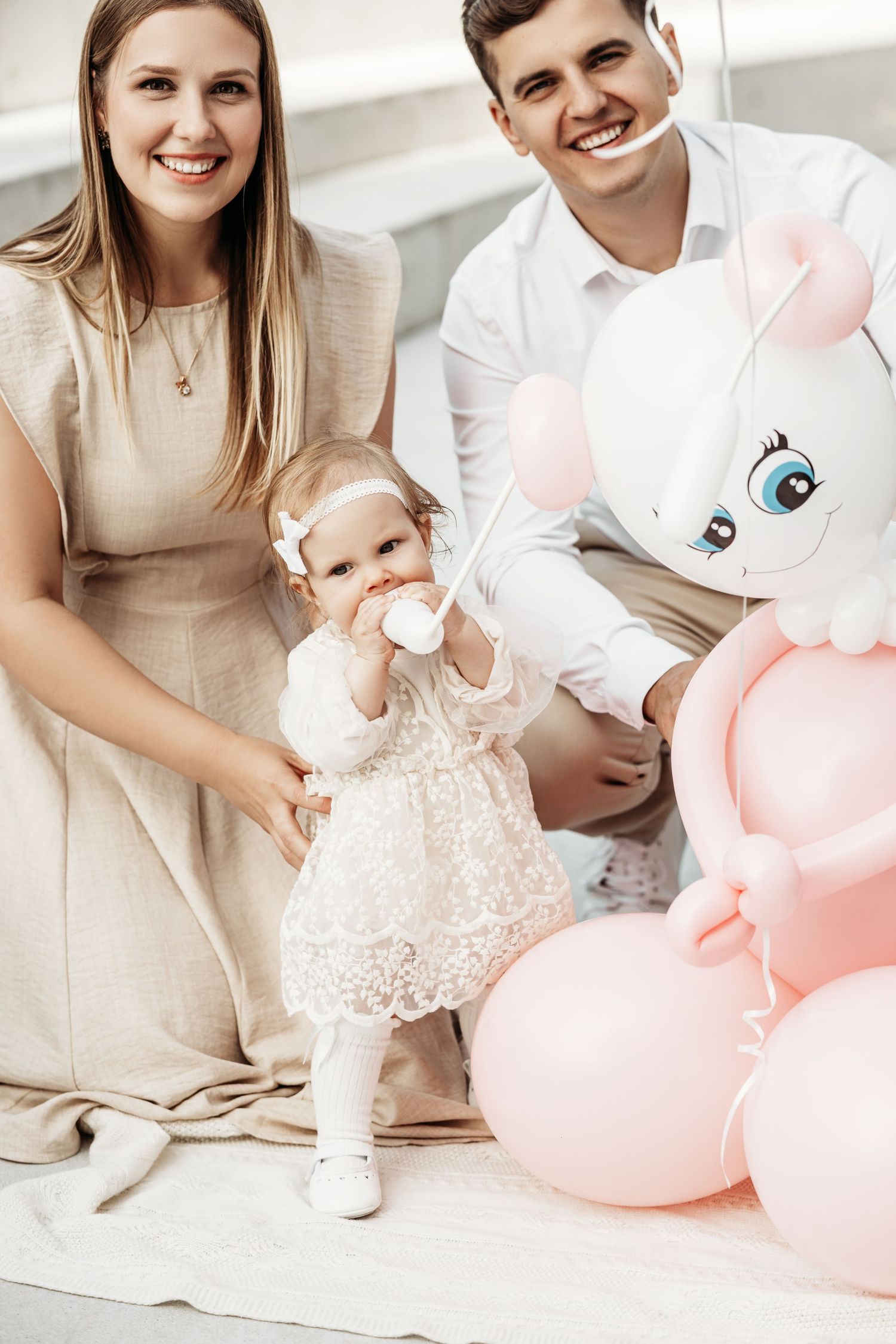 A bright family photo session with cream and pink decor featuring a small baby in white lace.