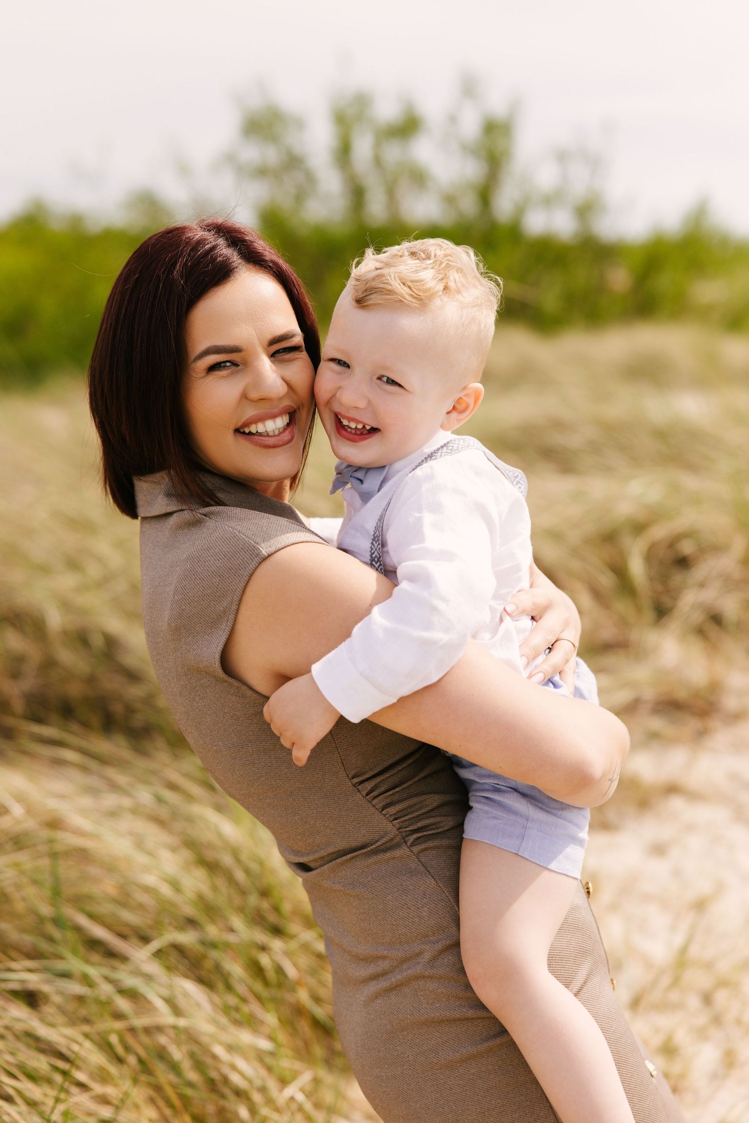 Candid moments captured in tall grass during a summer outdoor photo session.