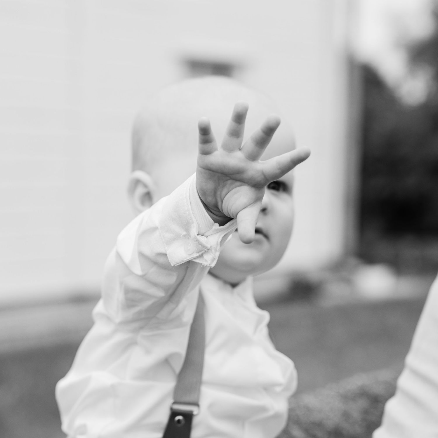 Black and white photo of a person in white shirt holding up their hand in a stop gesture.