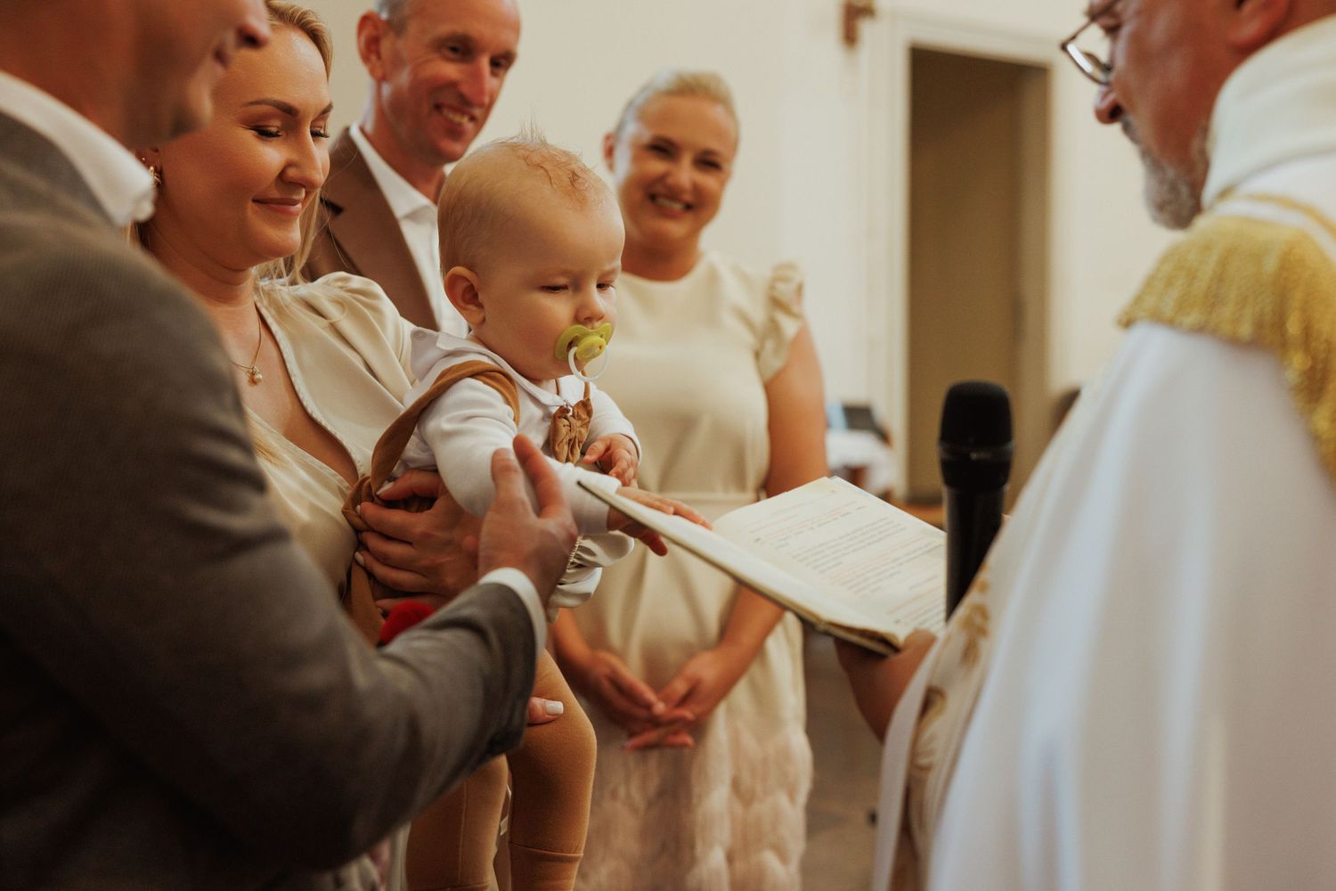 A candid moment captured during a wedding celebration showing guests interacting in a warmly lit indoor setting.
