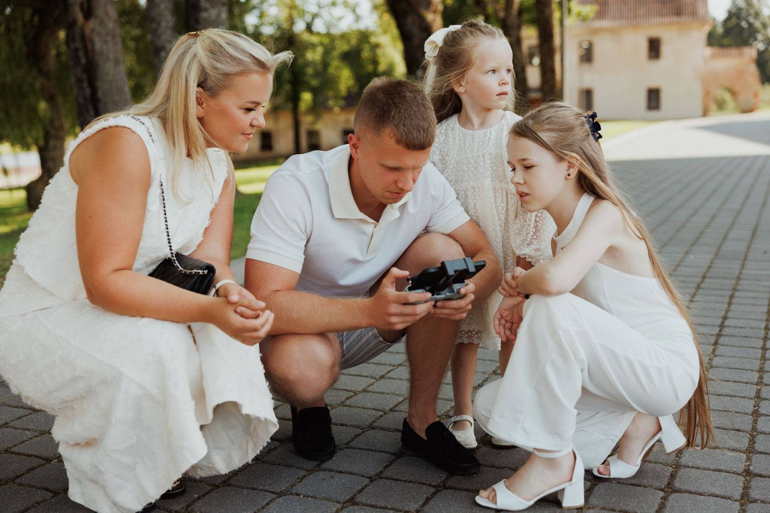 Family sitting together on outdoor stone pavement during golden hour.