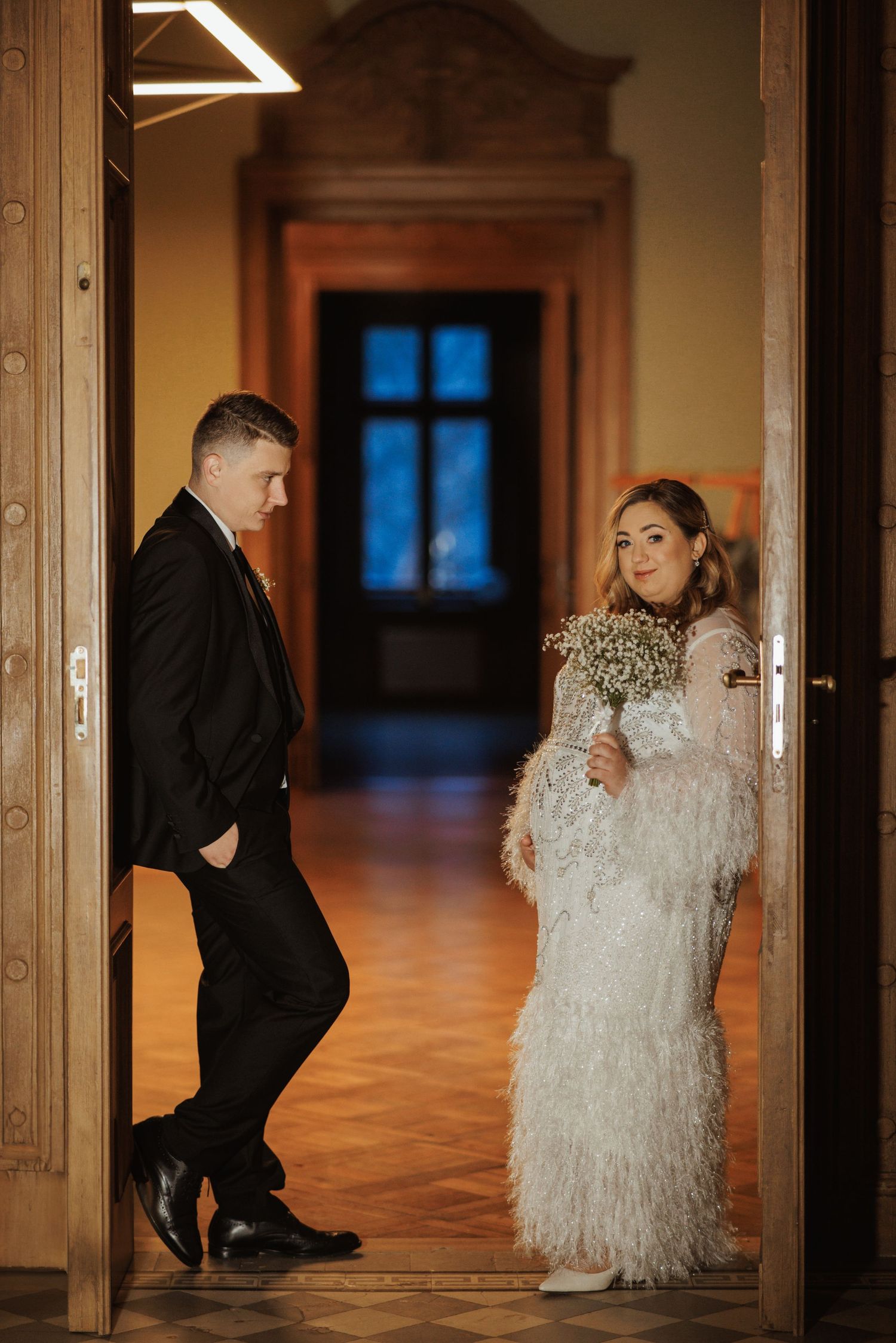 Intimate wedding portraits in warm-lit hallway with wooden columns.