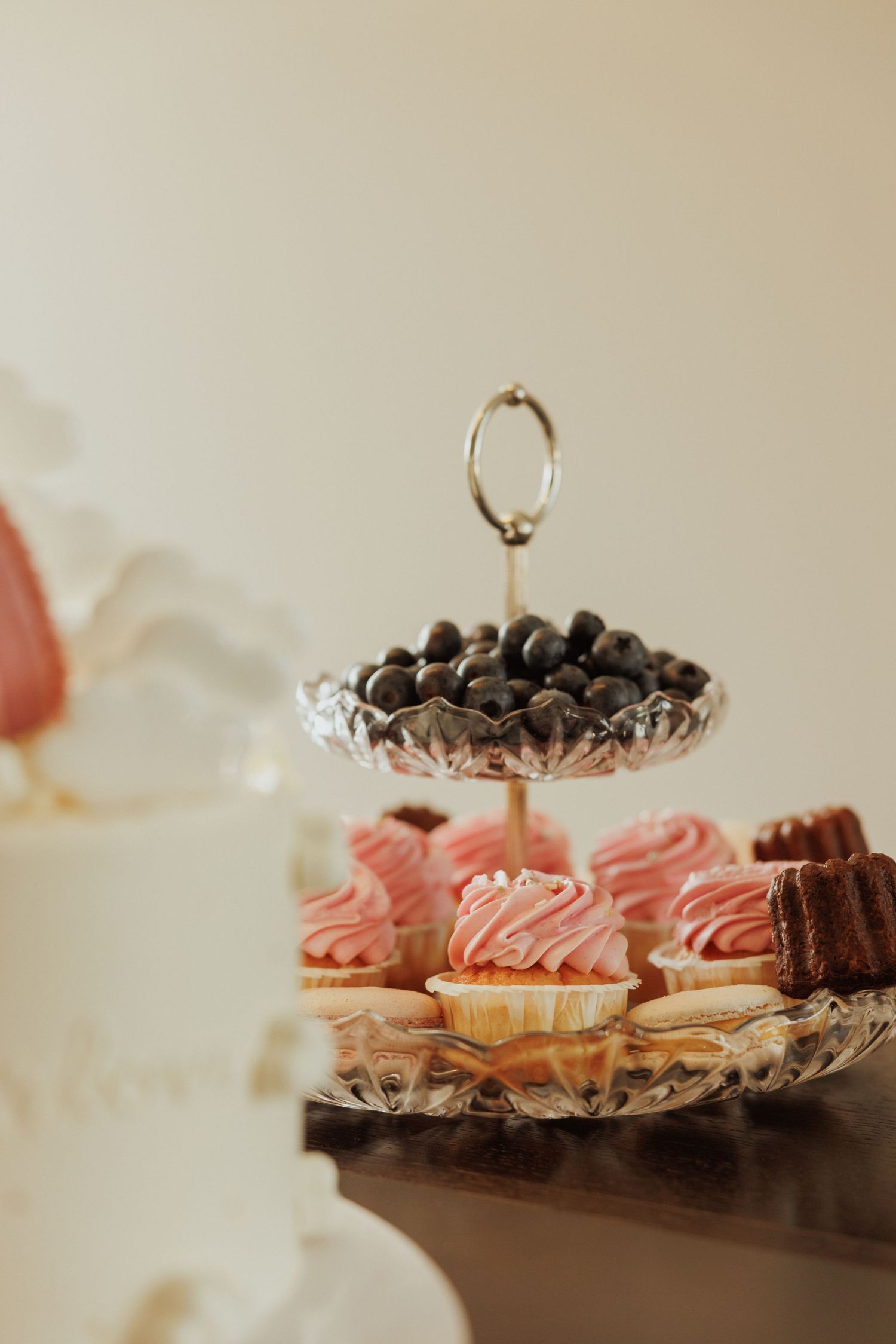 Pink frosted desserts and chocolate treats arranged on crystal cake stands.