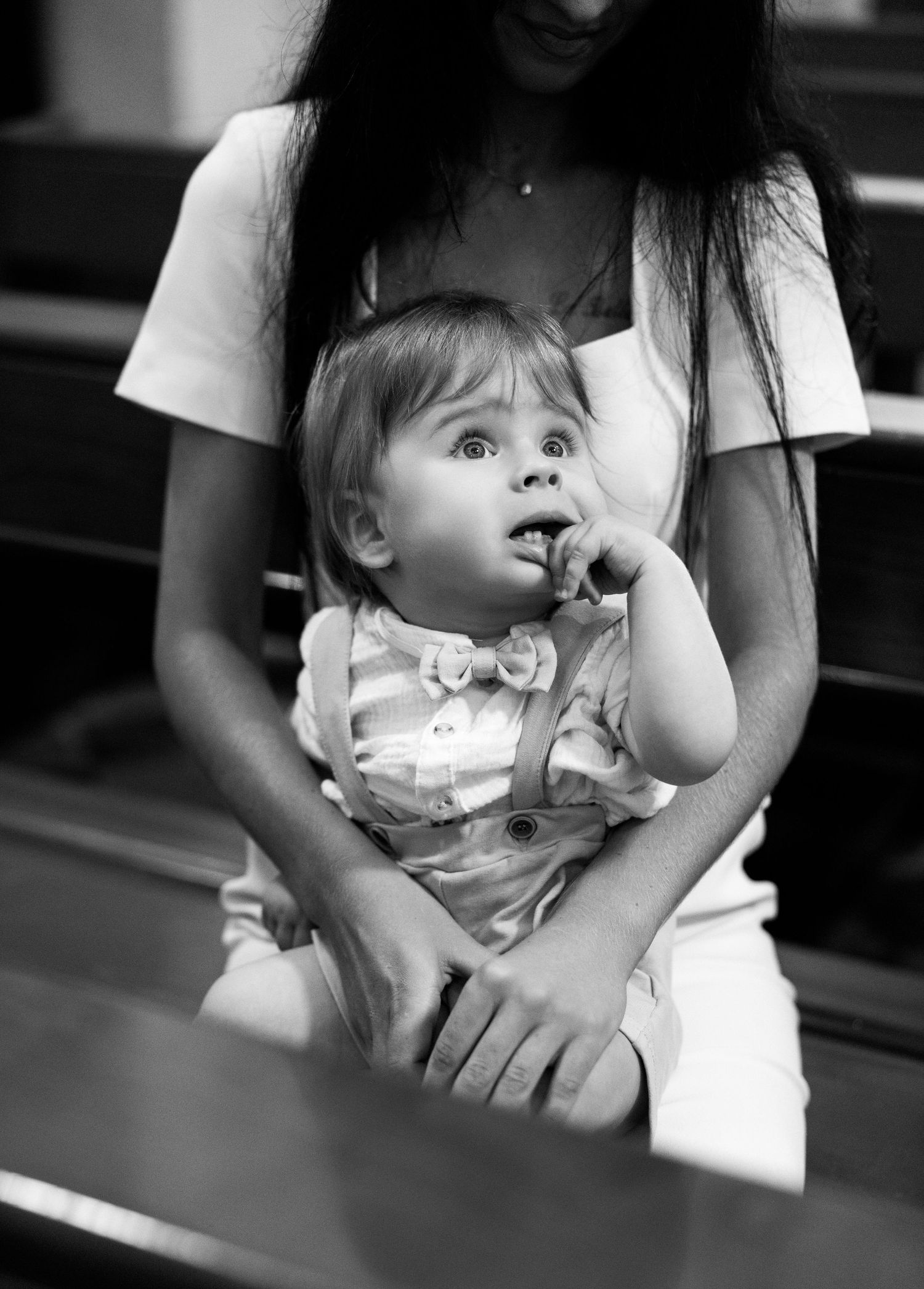 Black and white photo sequence showing a baby sitting on someone's lap while sucking their thumb.