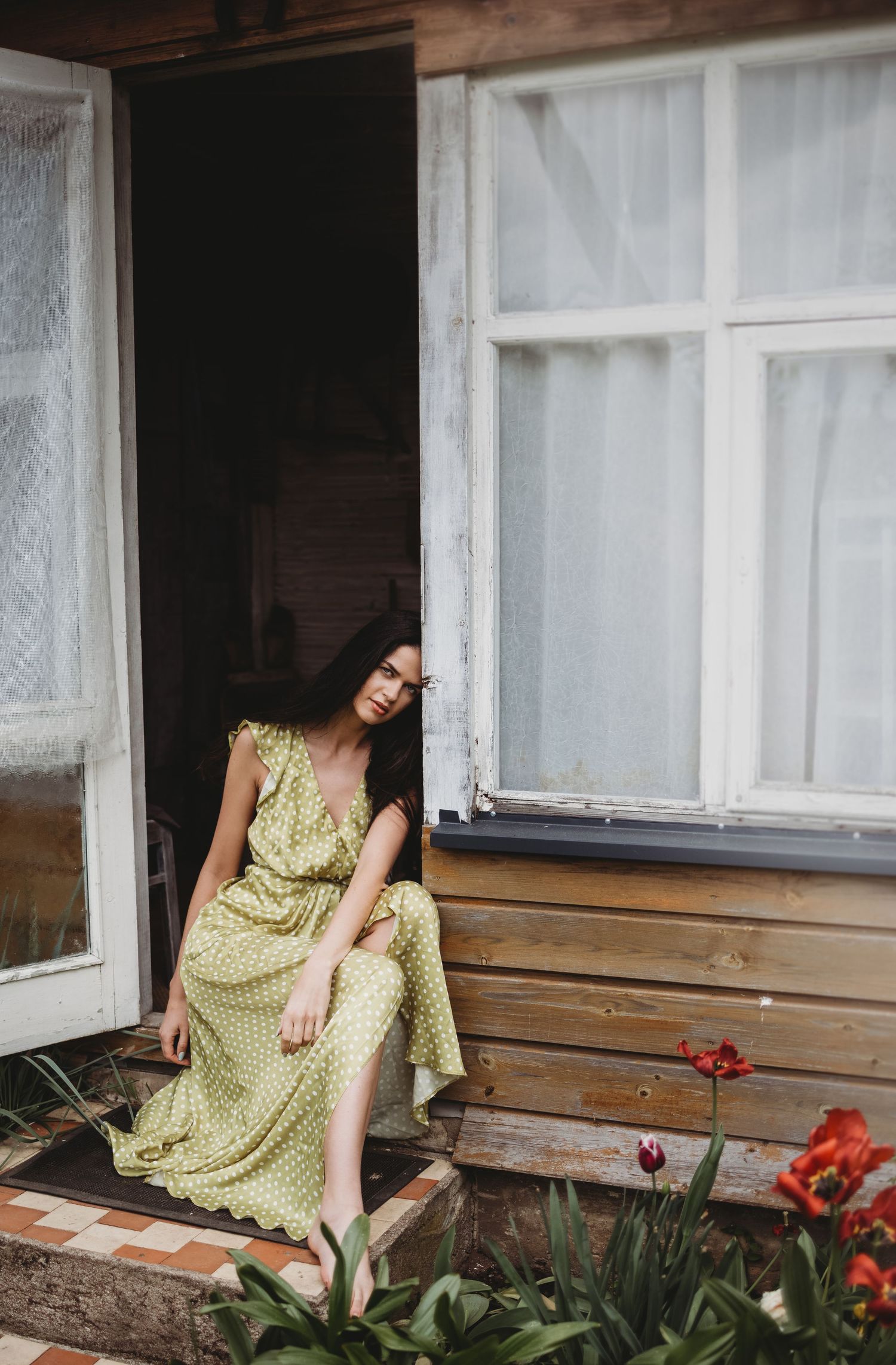 Cottage porch scene with red flowers and white windows framing a summer moment.