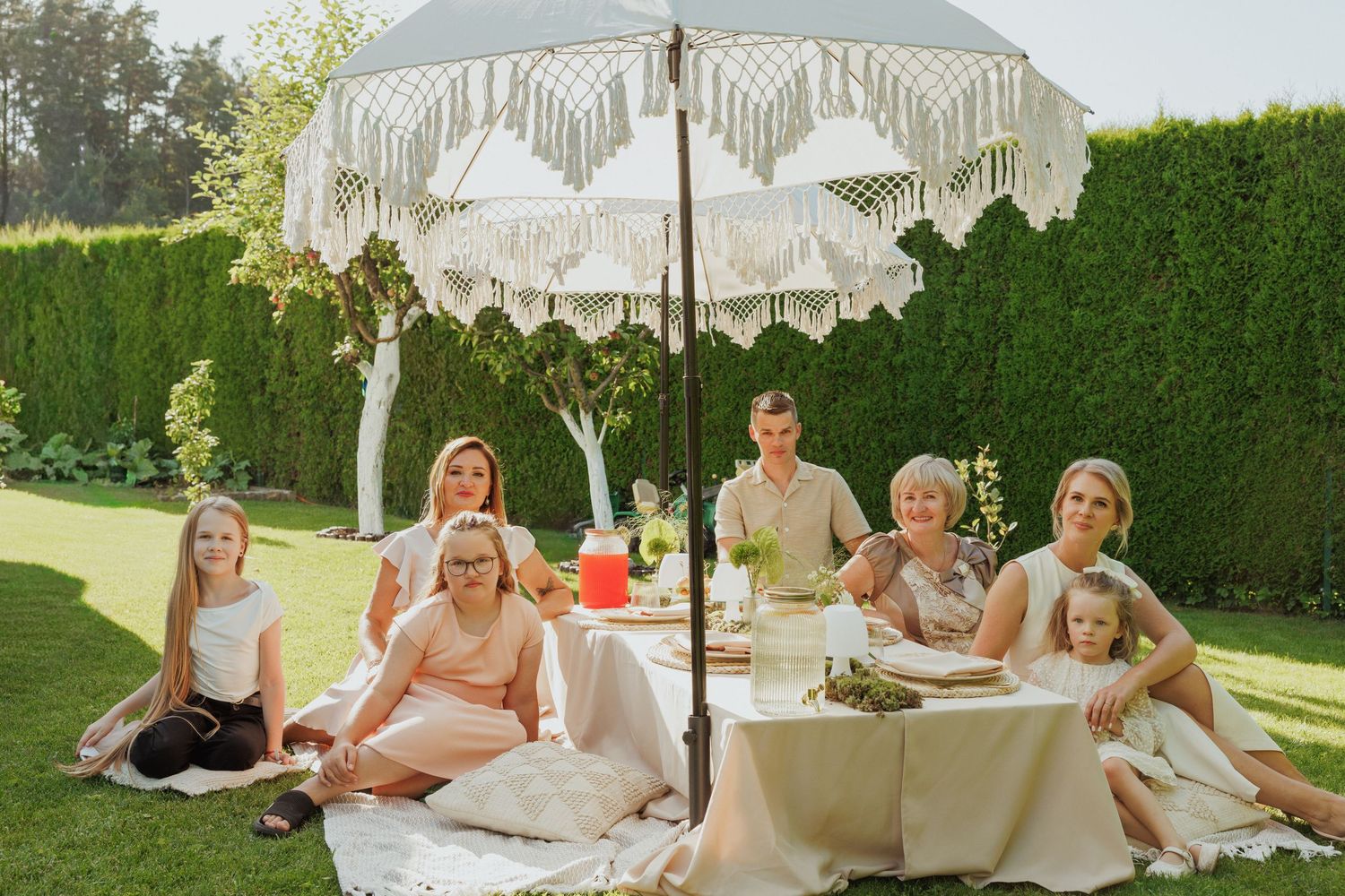 Garden party setup with guests relaxing under a fringed umbrella.