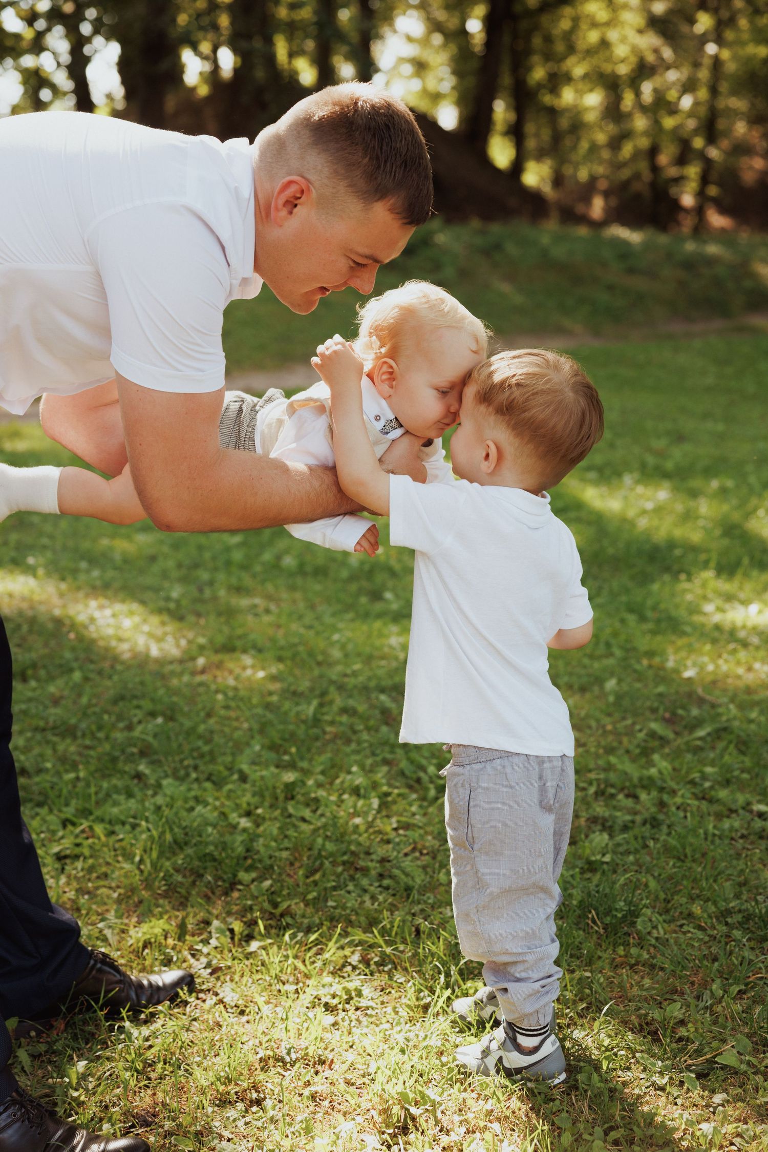 Sweet family moment captured outdoors as they play together in sunlit garden.