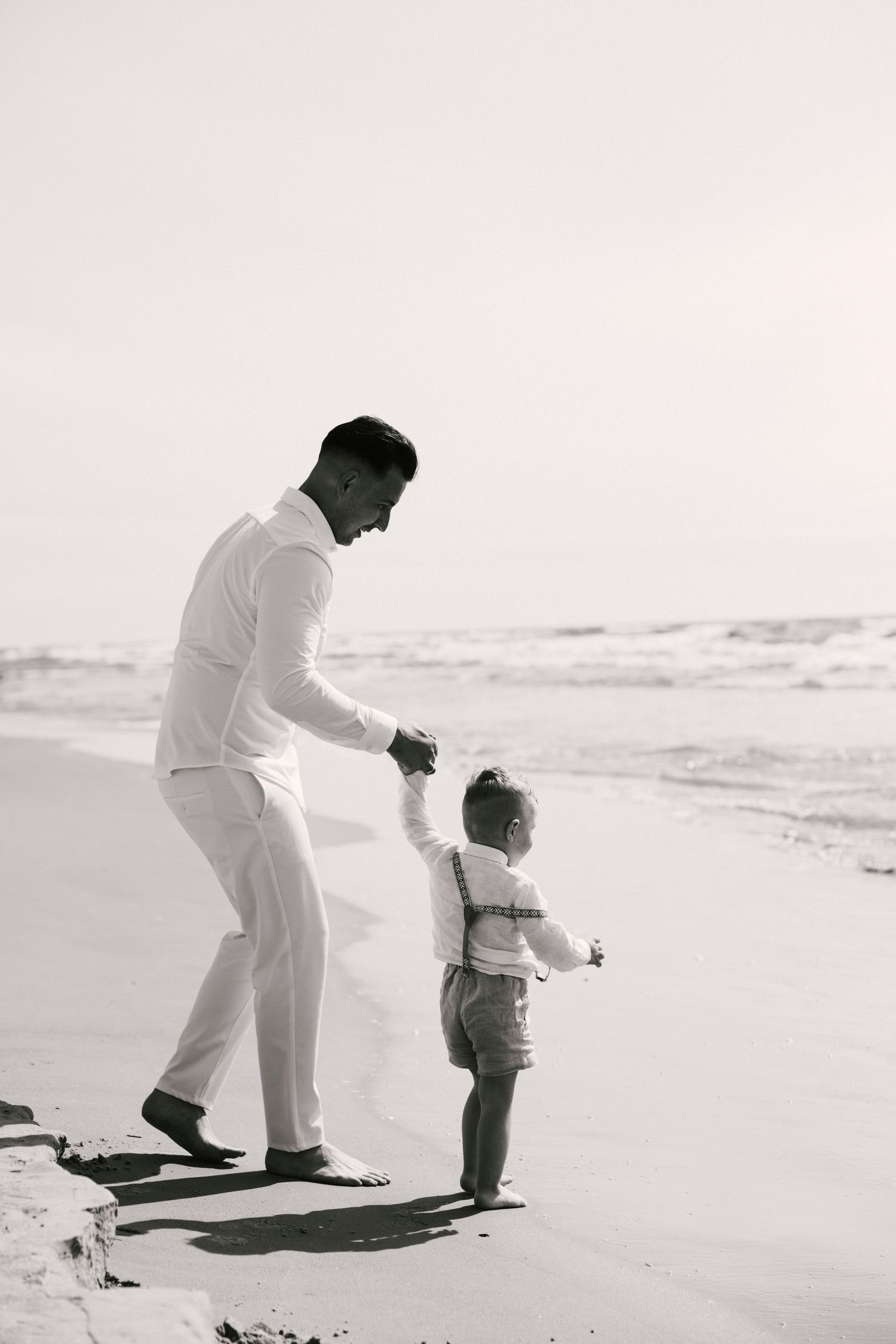Black and white photos of parent and child playing together on beach boardwalk.