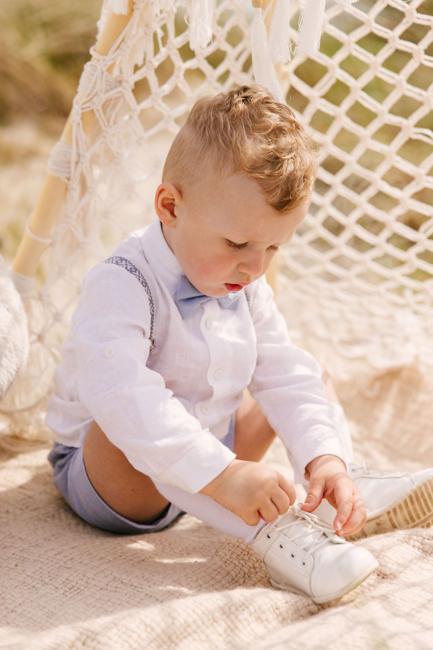 Child playing in sand near decorative lattice structure on beach.