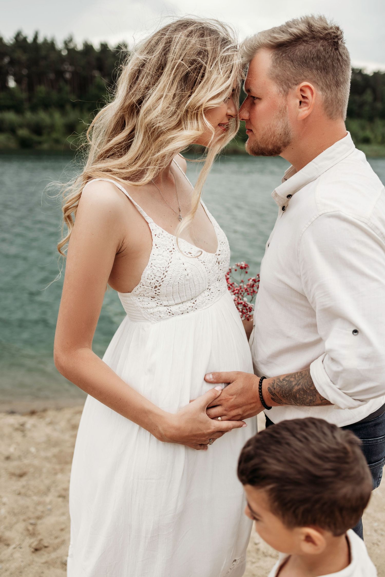 Tender family moment captured on a beach with white clothing and natural lighting.