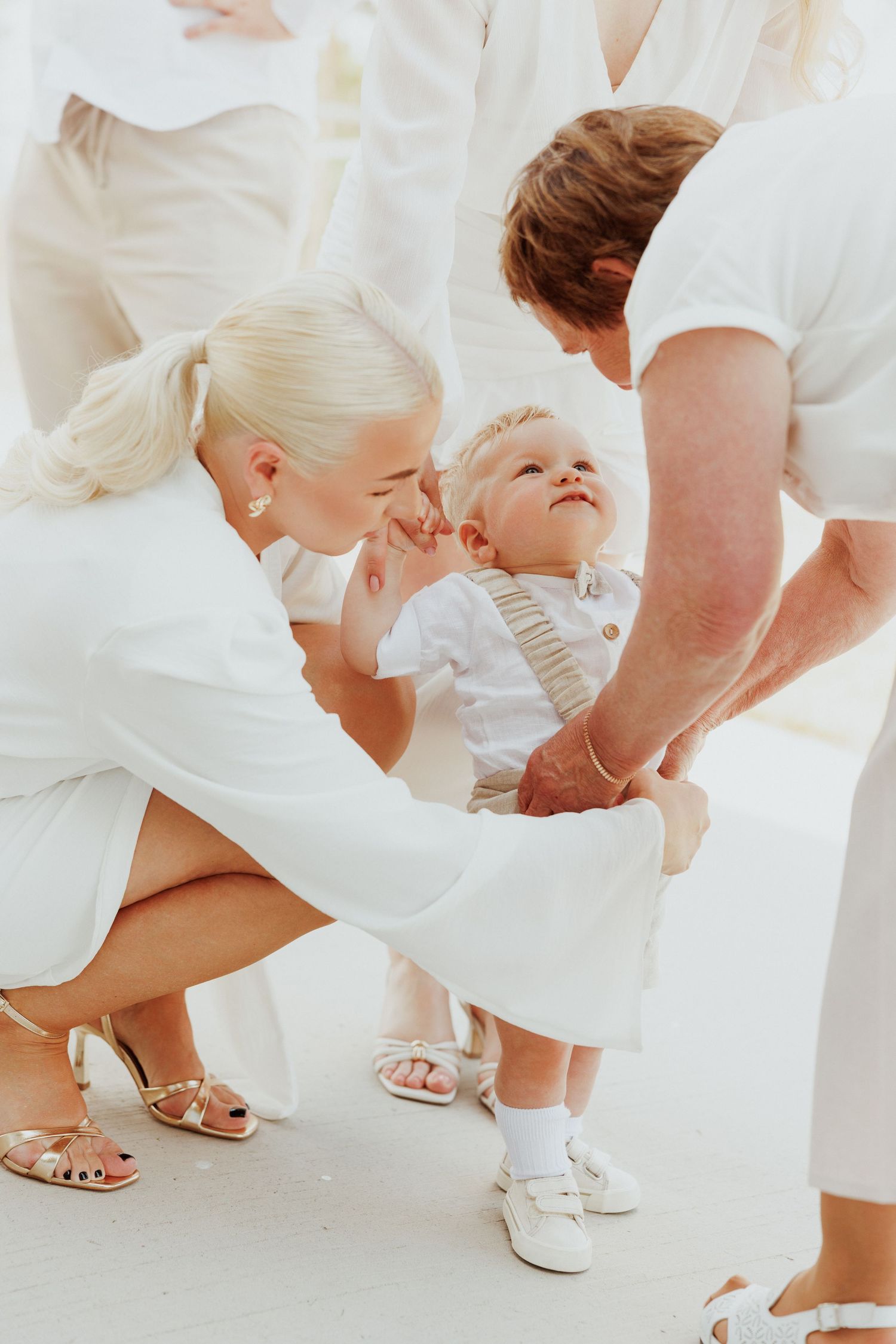 Group of people in white outfits bending down to show off their matching sandals and shoes.