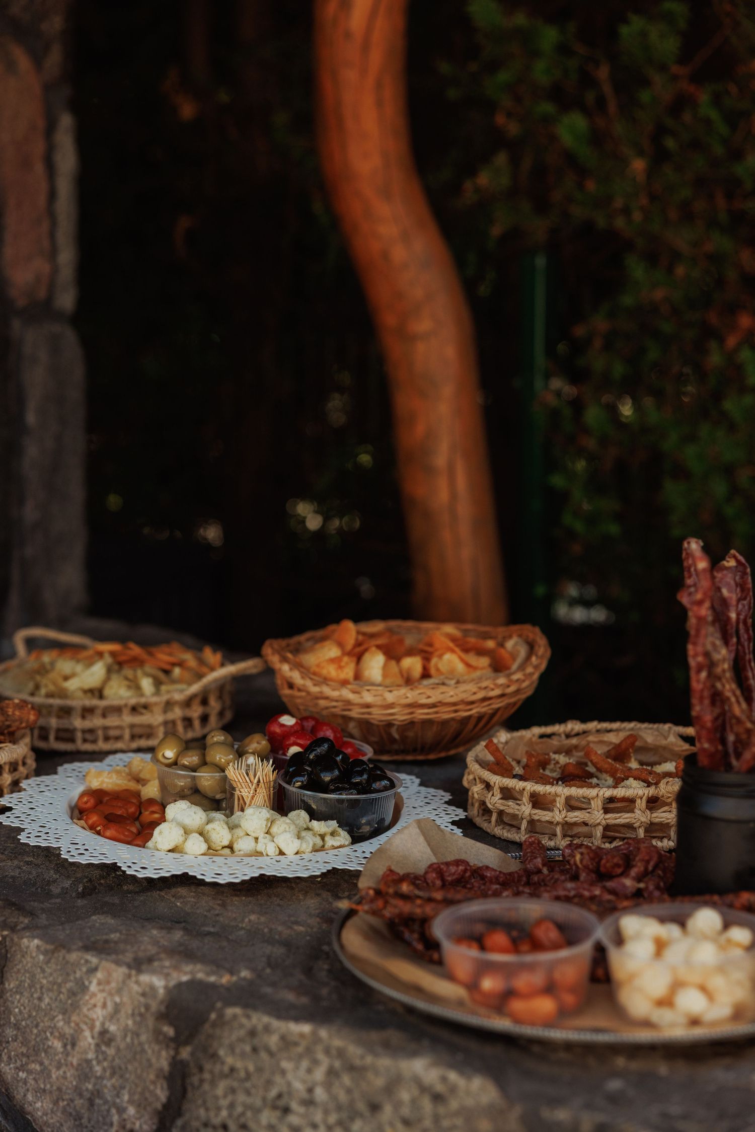 Rustic appetizer spread featuring charcuterie boards and snacks displayed on stone surfaces.