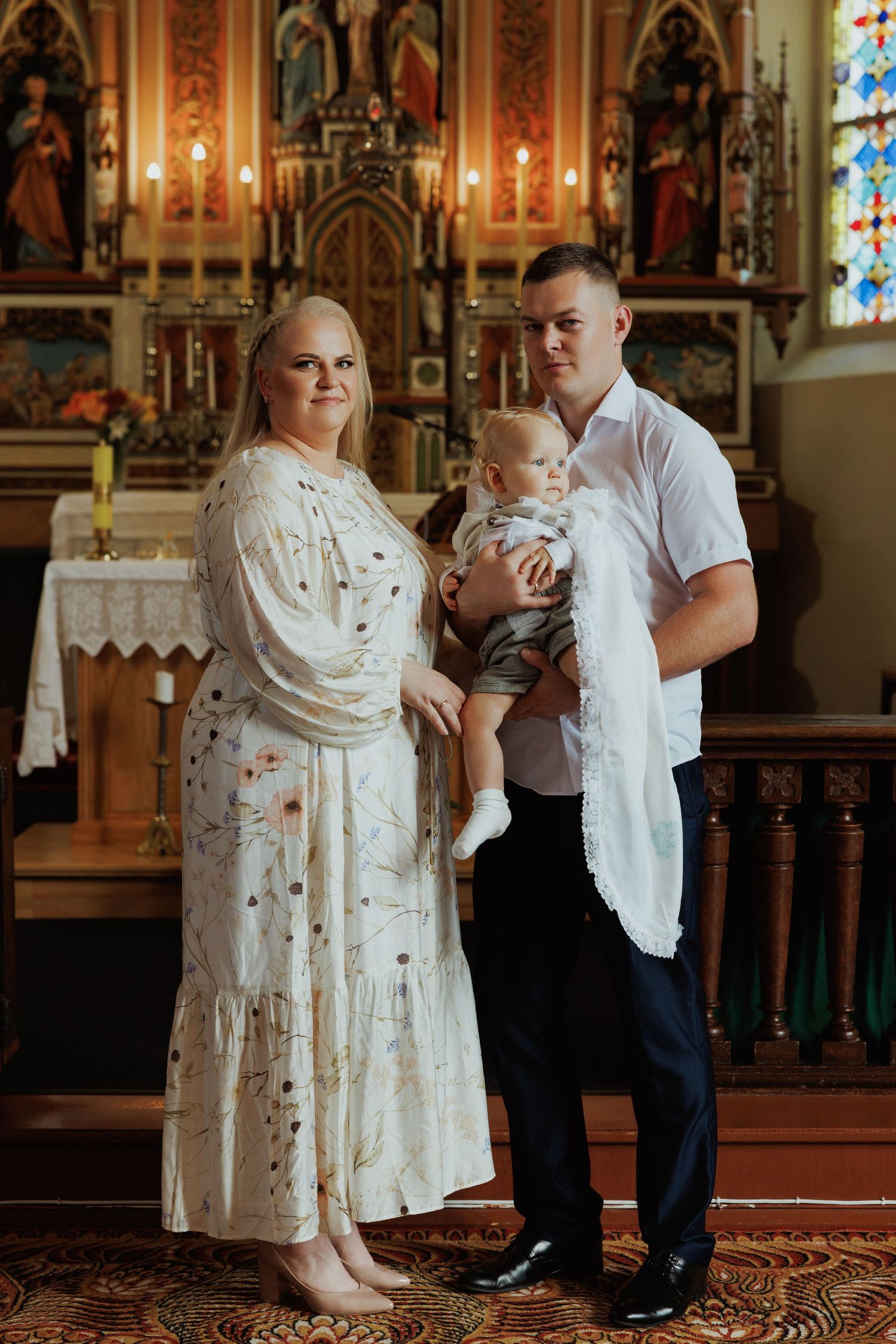 Family standing together in traditional church setting with ornate altar and stained glass windows.