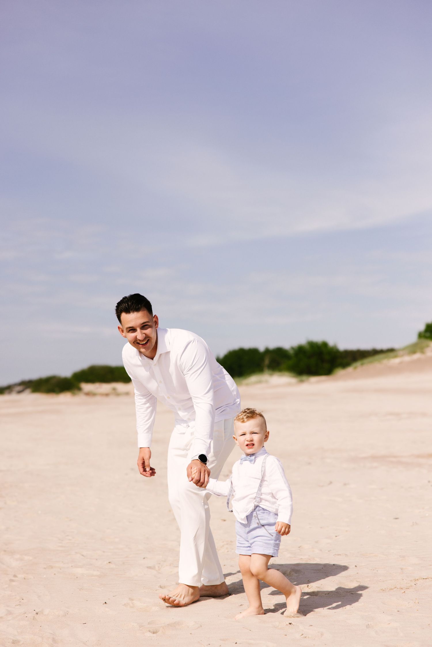 Parent and child playing together on sandy beach during bright sunny day.
