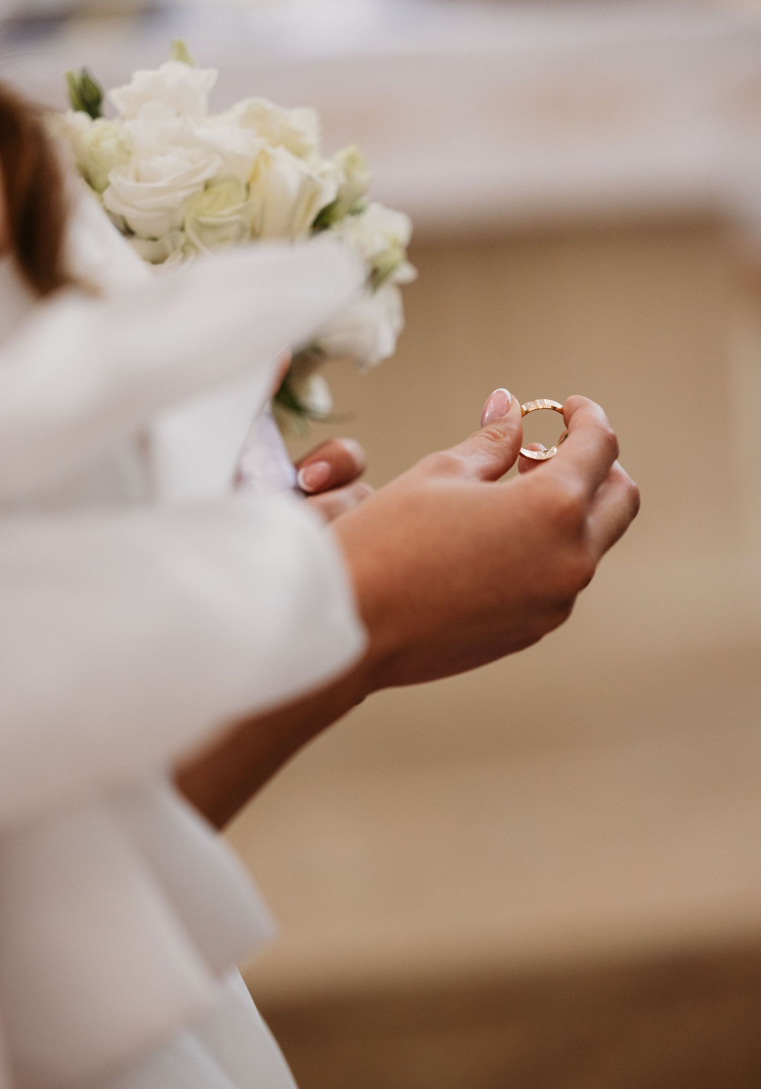 Close-up shot of hands holding delicate white flowers during a wedding ceremony.