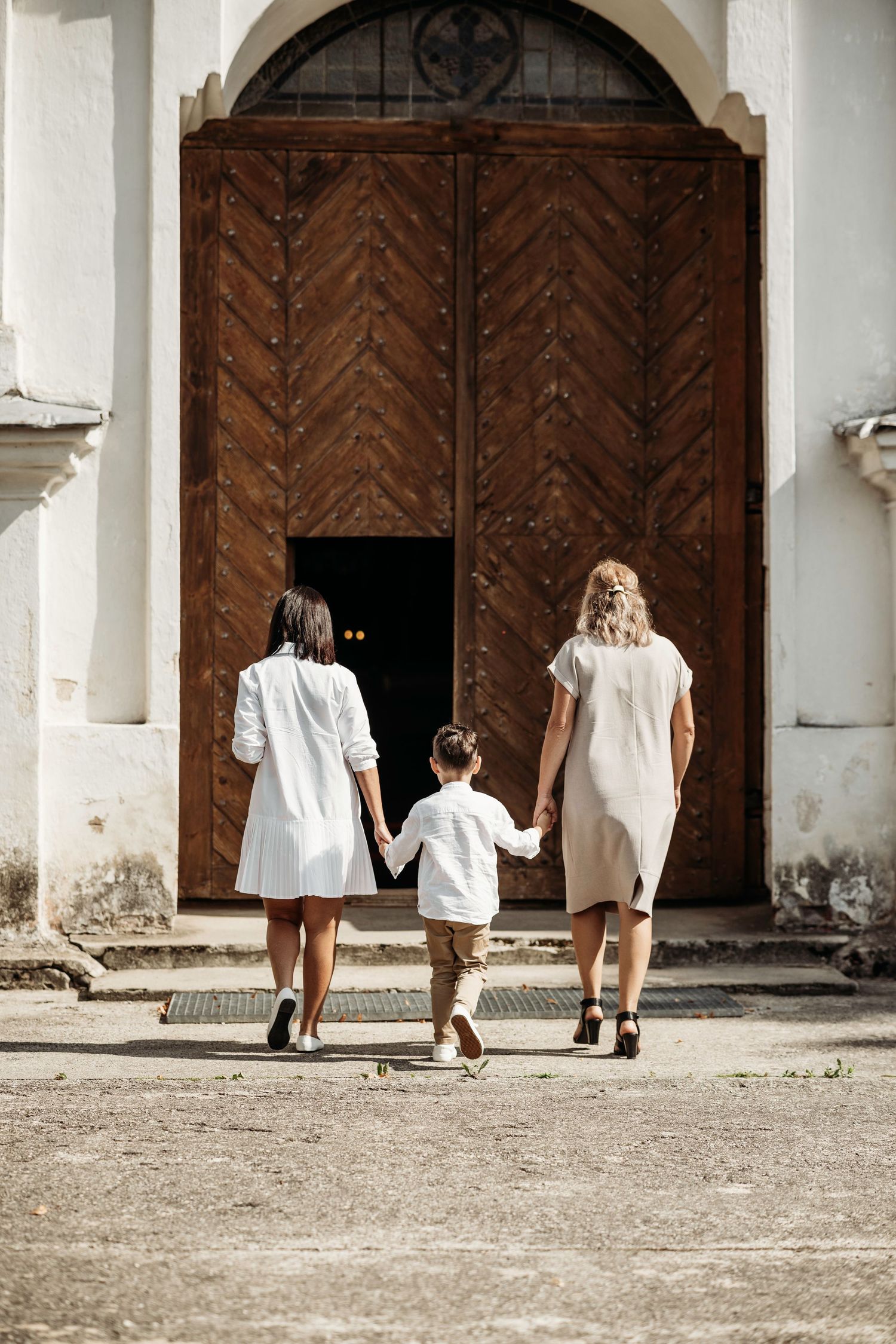 A sequence of people walking towards large wooden church doors in vintage-style photography.