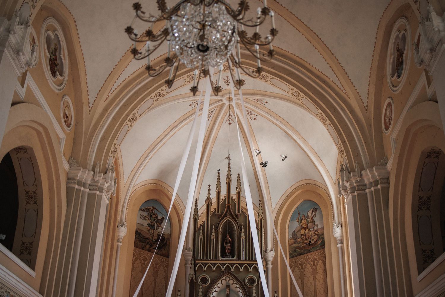 Gothic cathedral interior with ornate vaulted ceilings and arched architecture in warm sepia tones.