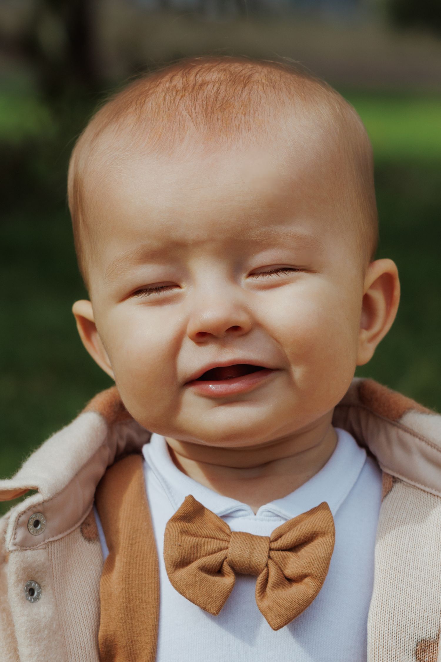 A series of close-up photos showing a smiling baby wearing a brown bowtie and beige cardigan.