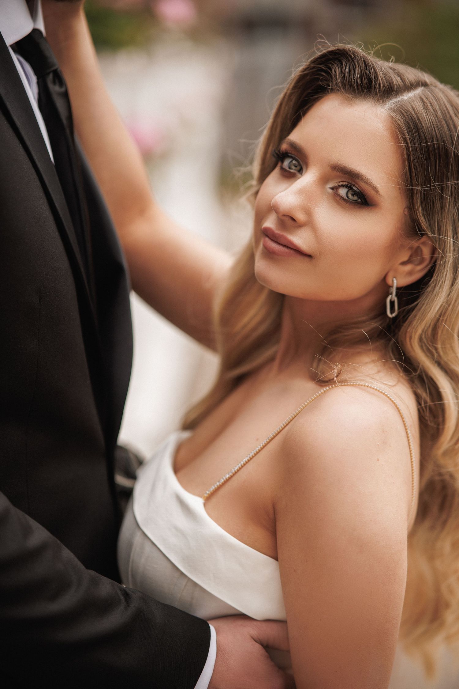 Close-up wedding portraits showing bride in white dress with elegant makeup and jewelry.