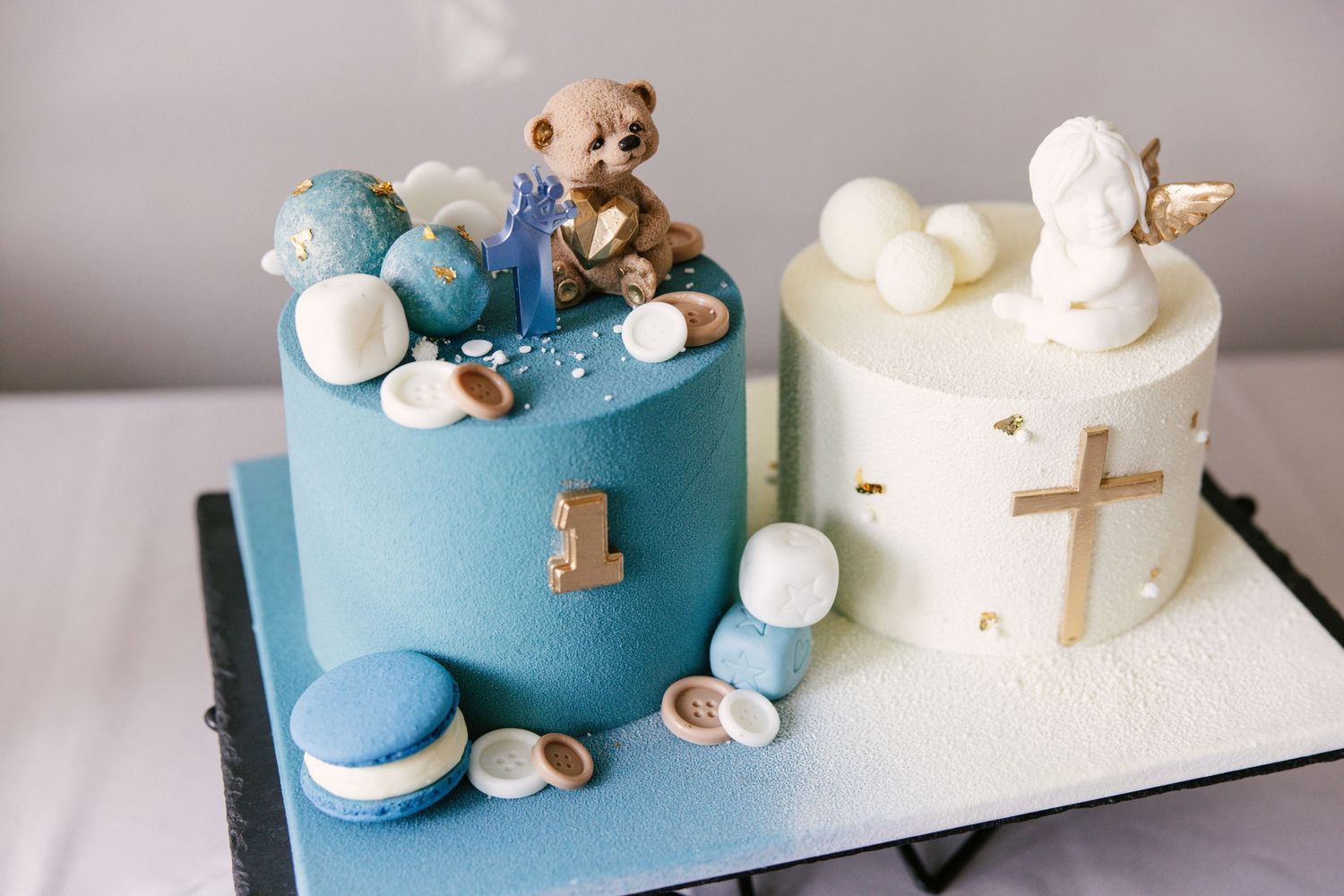 Modern blue and white celebration cake decorated with small teddy bears and geometric designs.