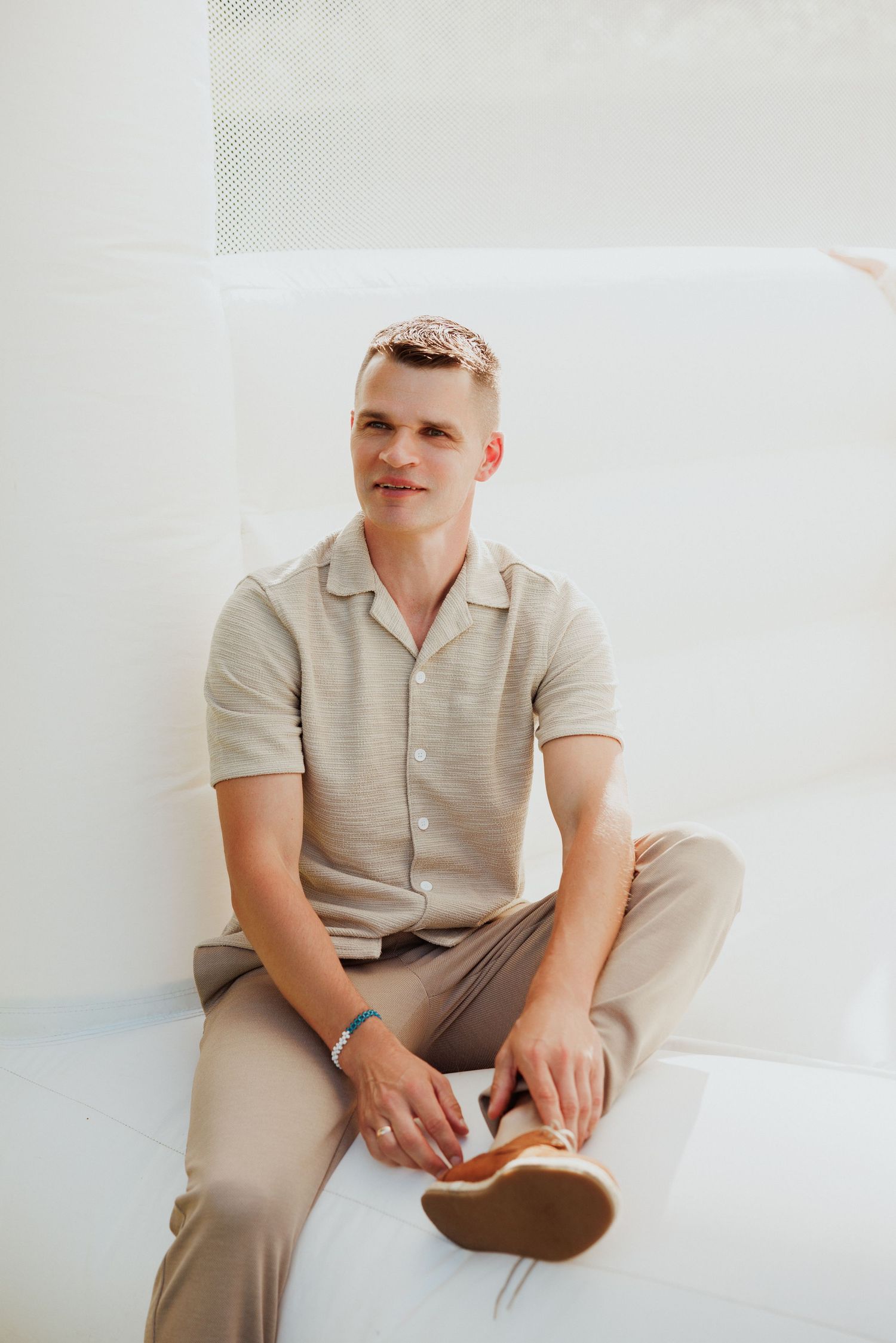 A person in neutral beige tones sits casually against a white background in a collage of four similar poses.